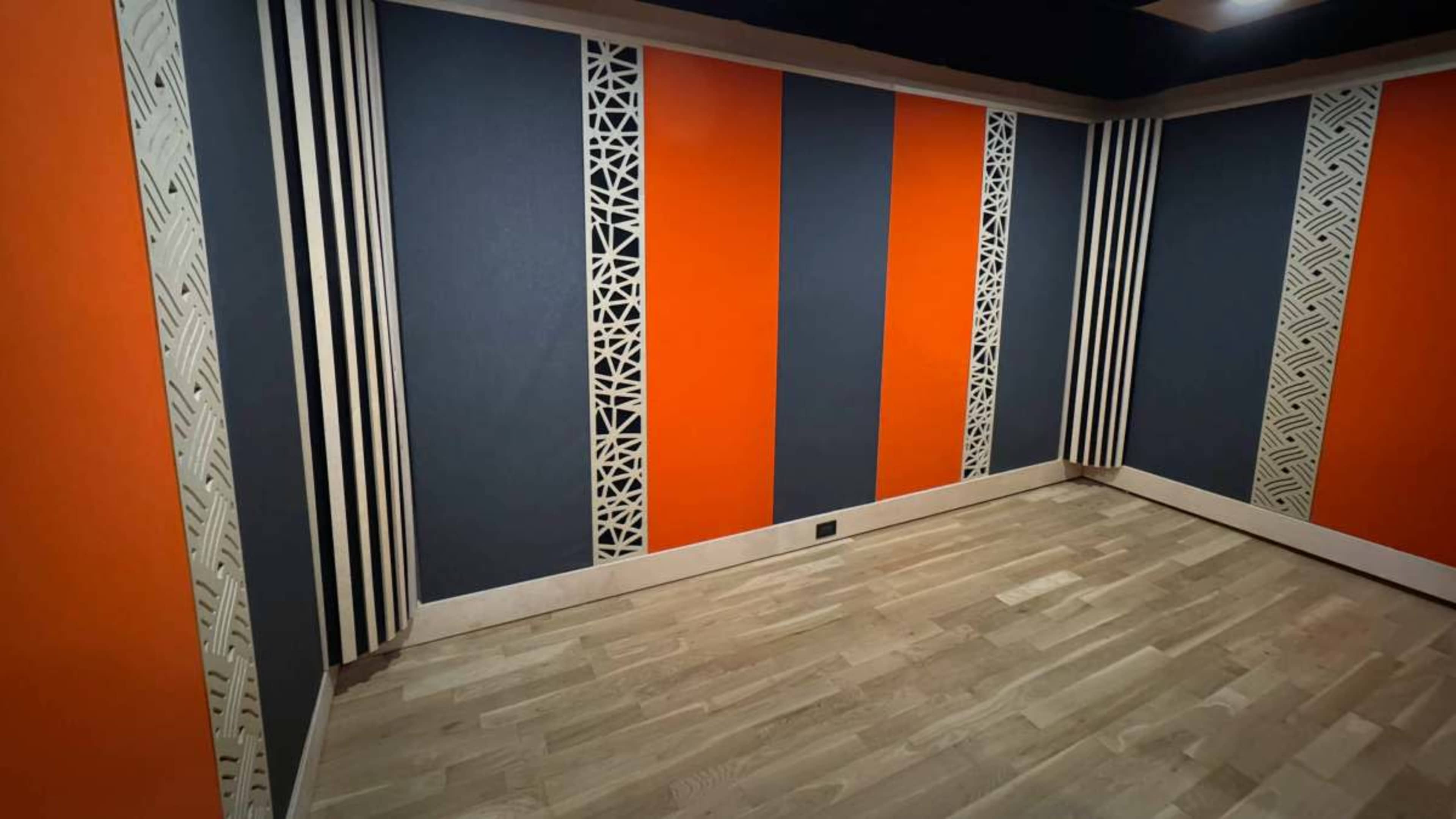 The image shows a spacious room featuring orange and blue patterned walls with decorative paneling and wooden flooring.