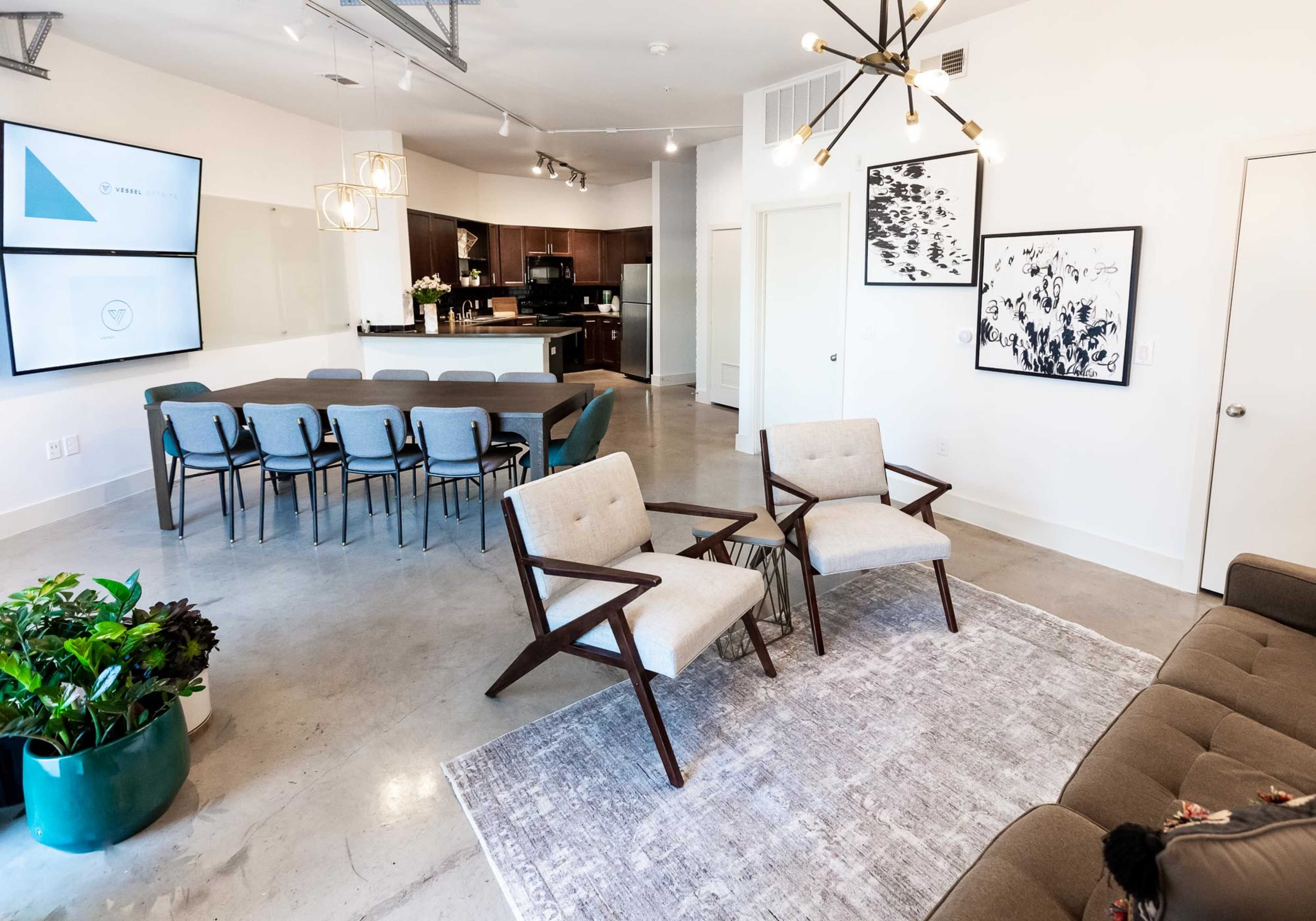 A modern, open-concept interior with a dining table, kitchen area, and seating arrangements including two chairs and a sofa.