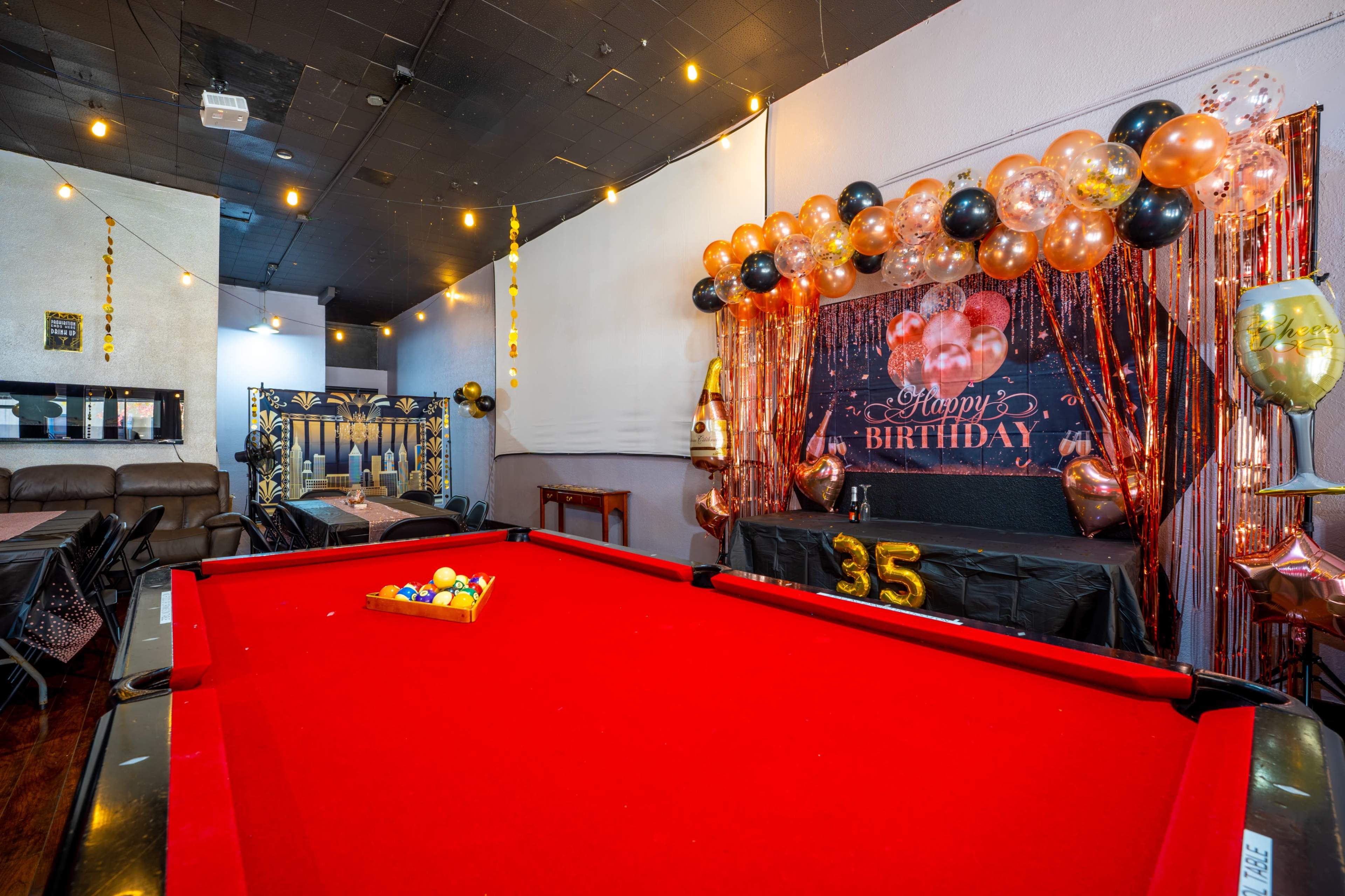 A party space features a red pool table in the foreground with birthday decorations, including a "Happy Birthday" banner and balloons in the background.