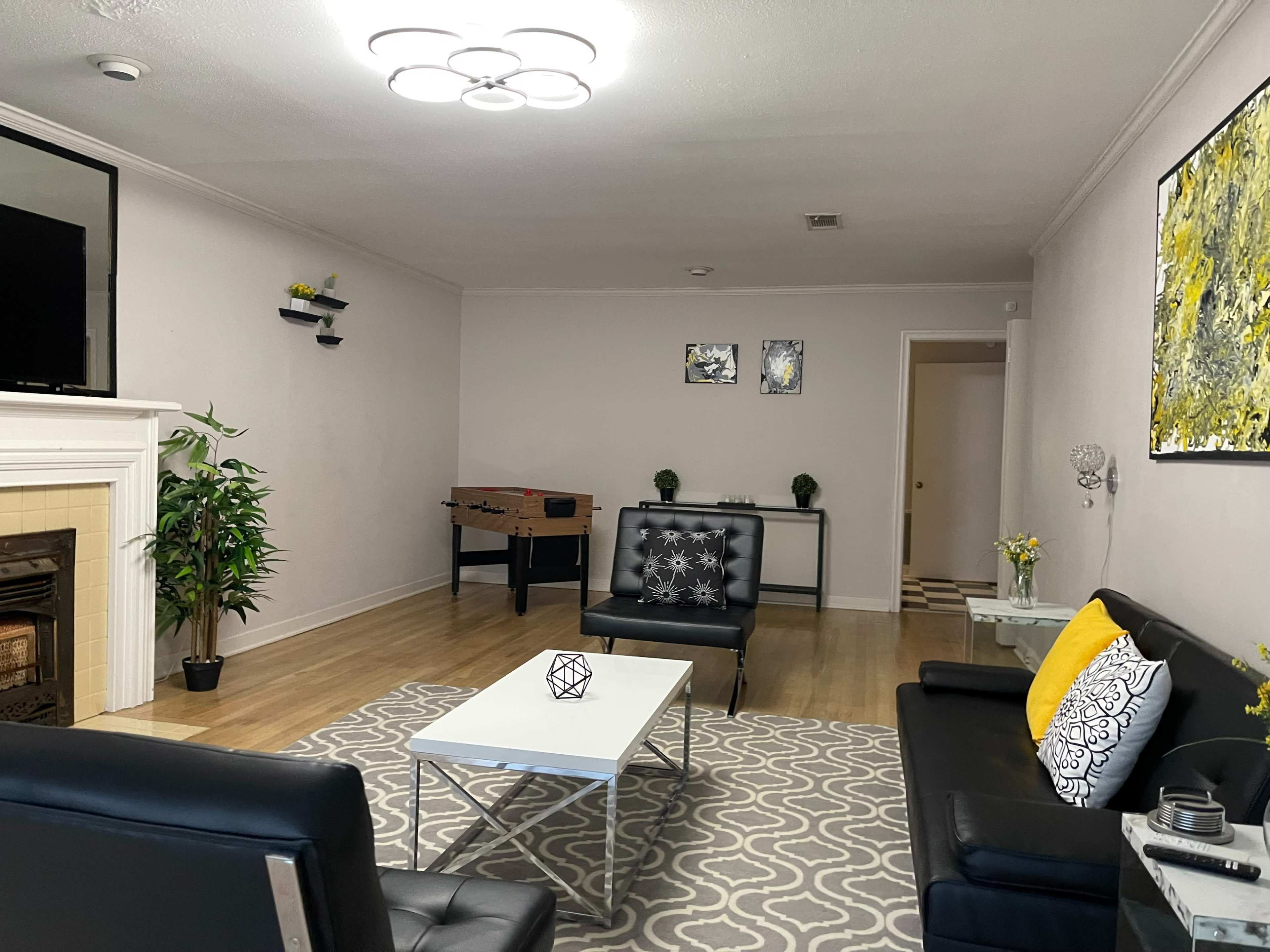 The room features a modern sitting area with black leather sofas, a coffee table, and a foosball table against the wall.