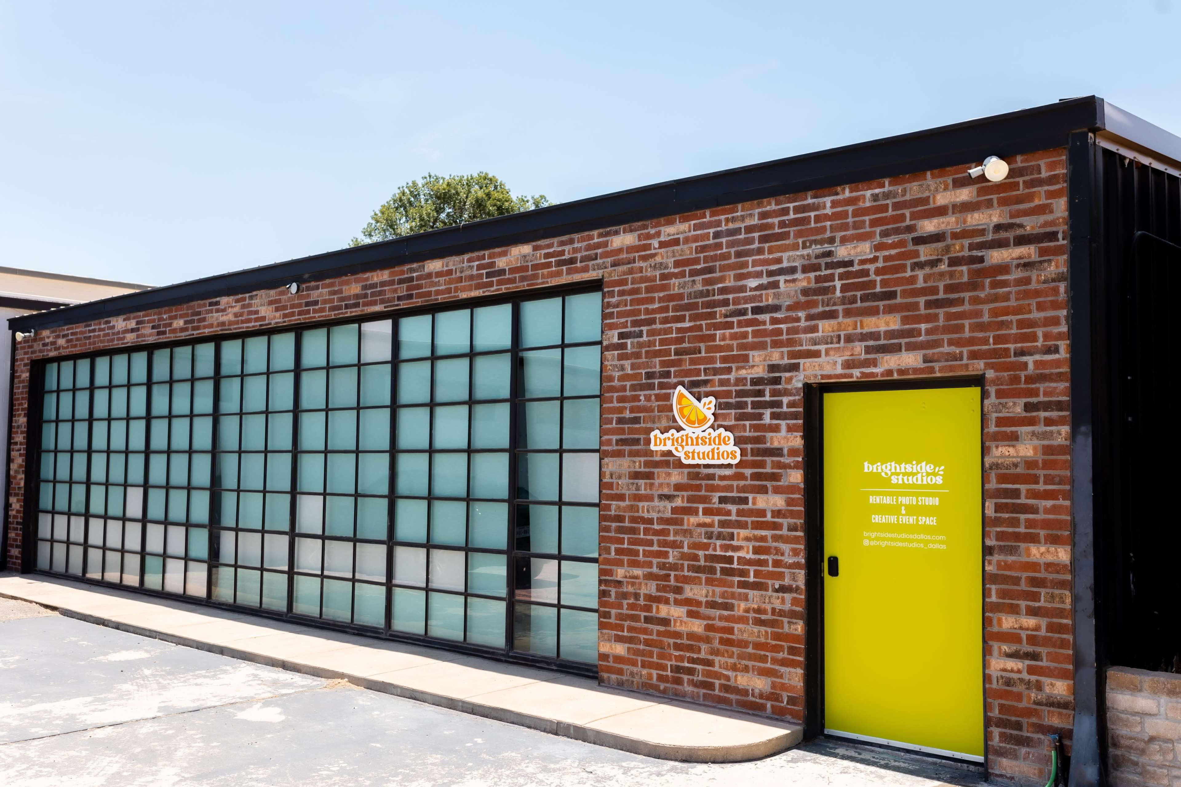 A brick building with large glass windows and a bright green door, labeled "Brightside Studios."