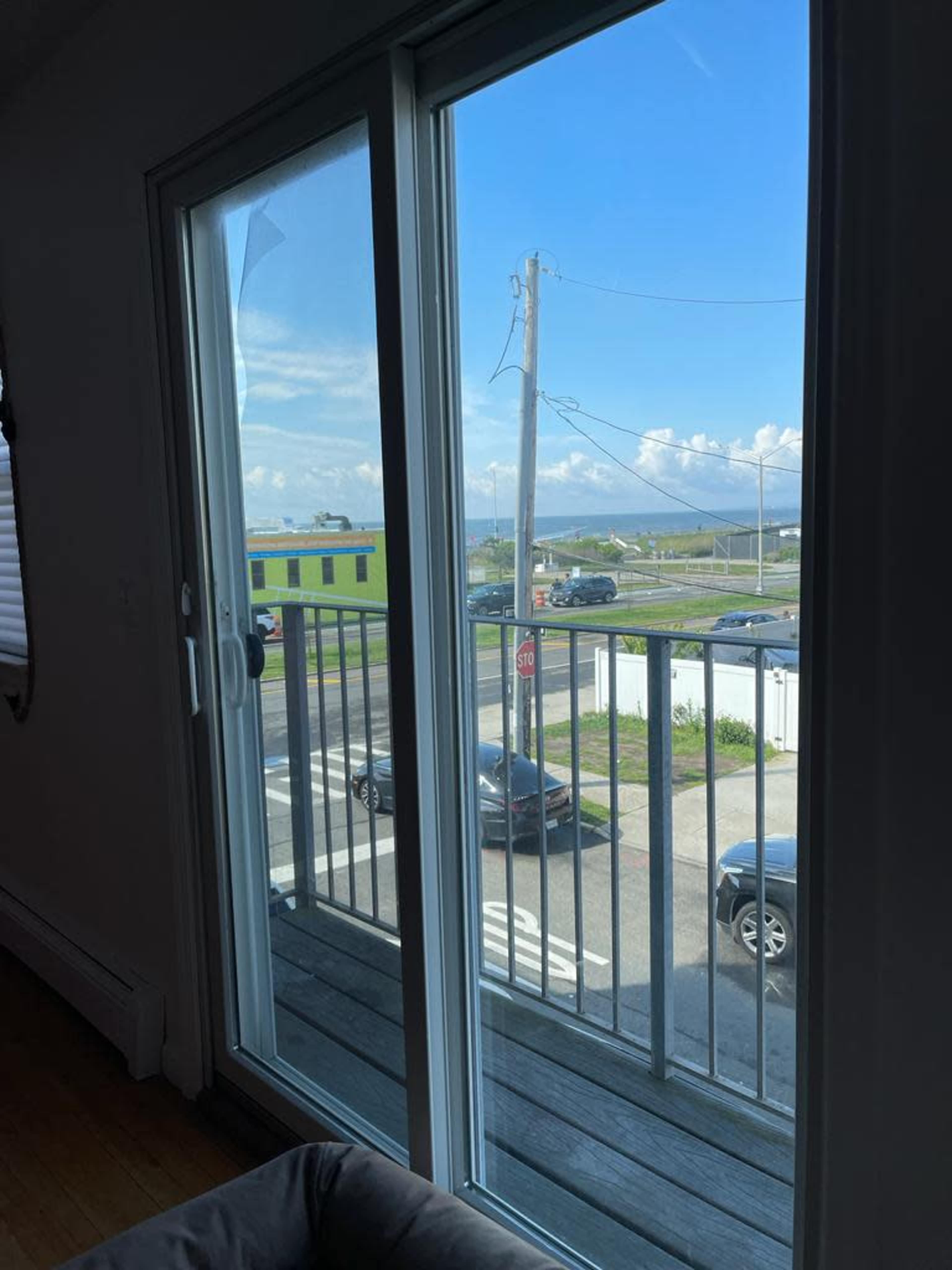 A view of a street and parked cars is visible through a sliding glass door with a balcony railing.