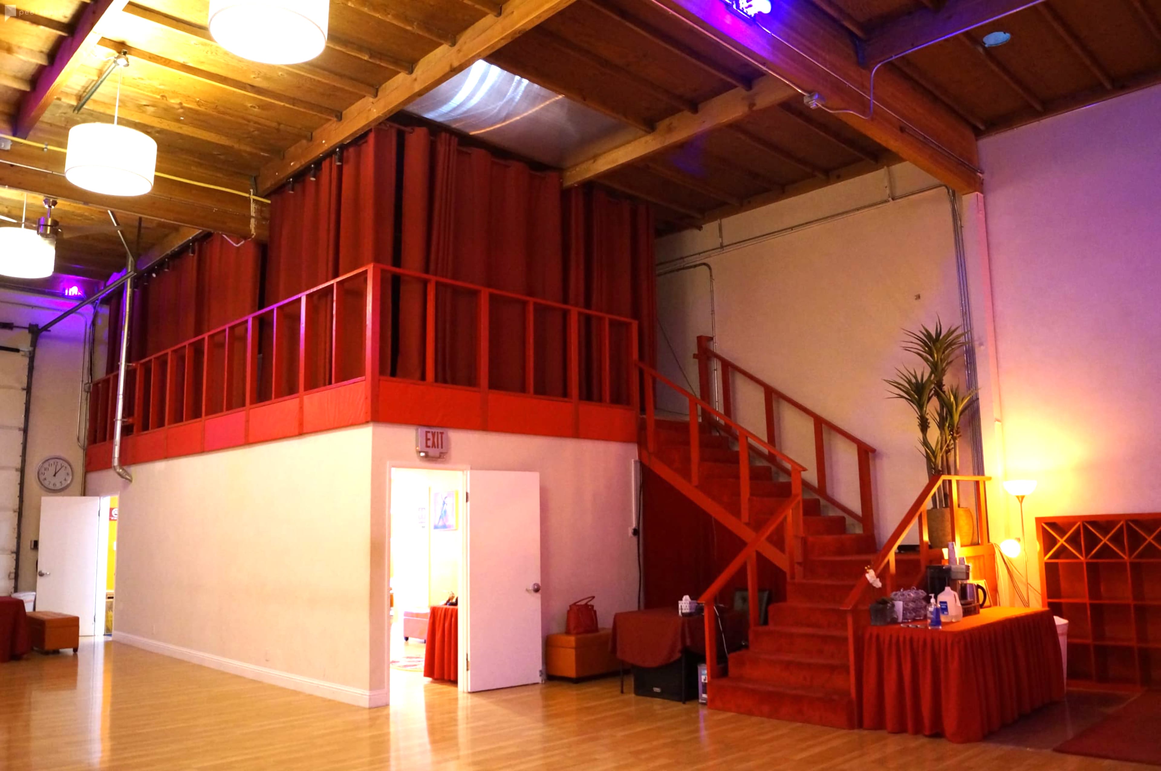An interior space featuring a red staircase and railing, with a seating area and a large curtain in the background.