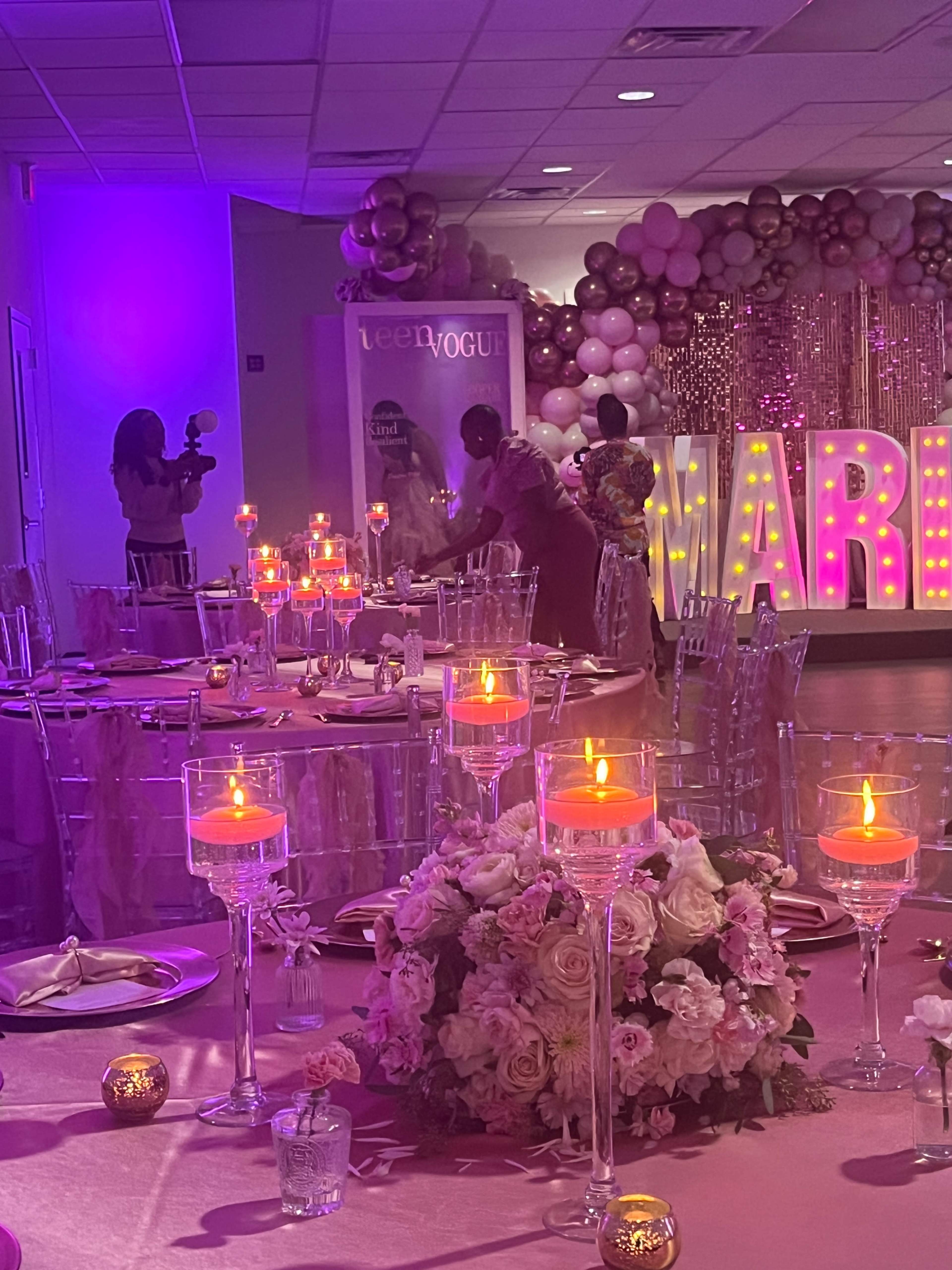 A decorated banquet hall features tables set with candles and floral arrangements, while large illuminated letters spell "MARRIED" in the background.