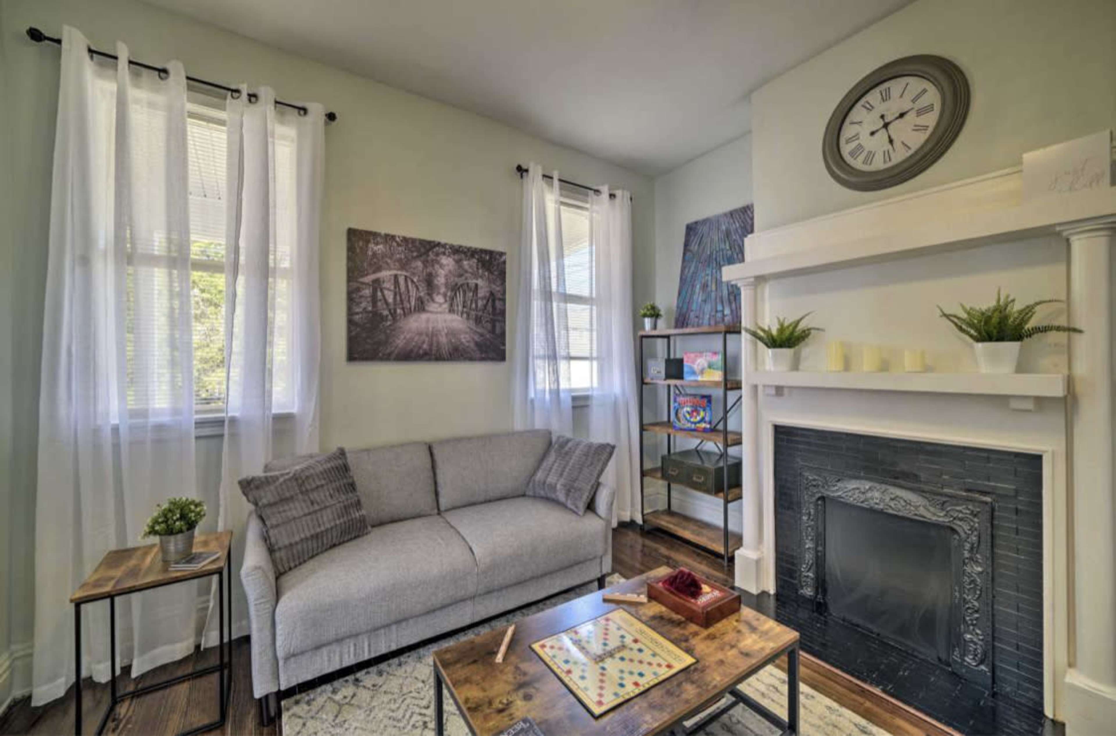 A cozy living room featuring a gray sofa, a wooden coffee table, and a fireplace with decorative elements.