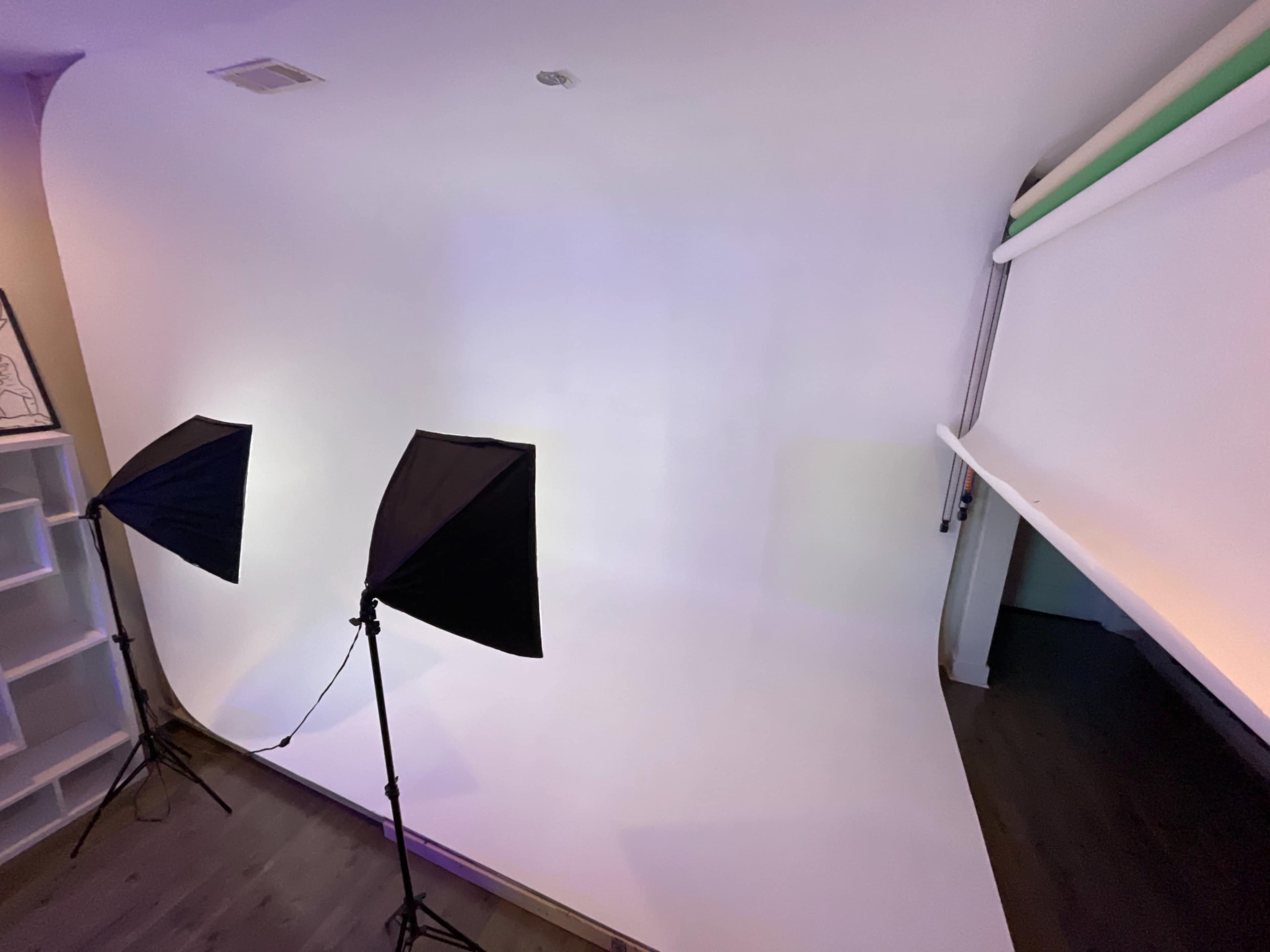 A photography studio with two studio lights positioned in front of a white backdrop.