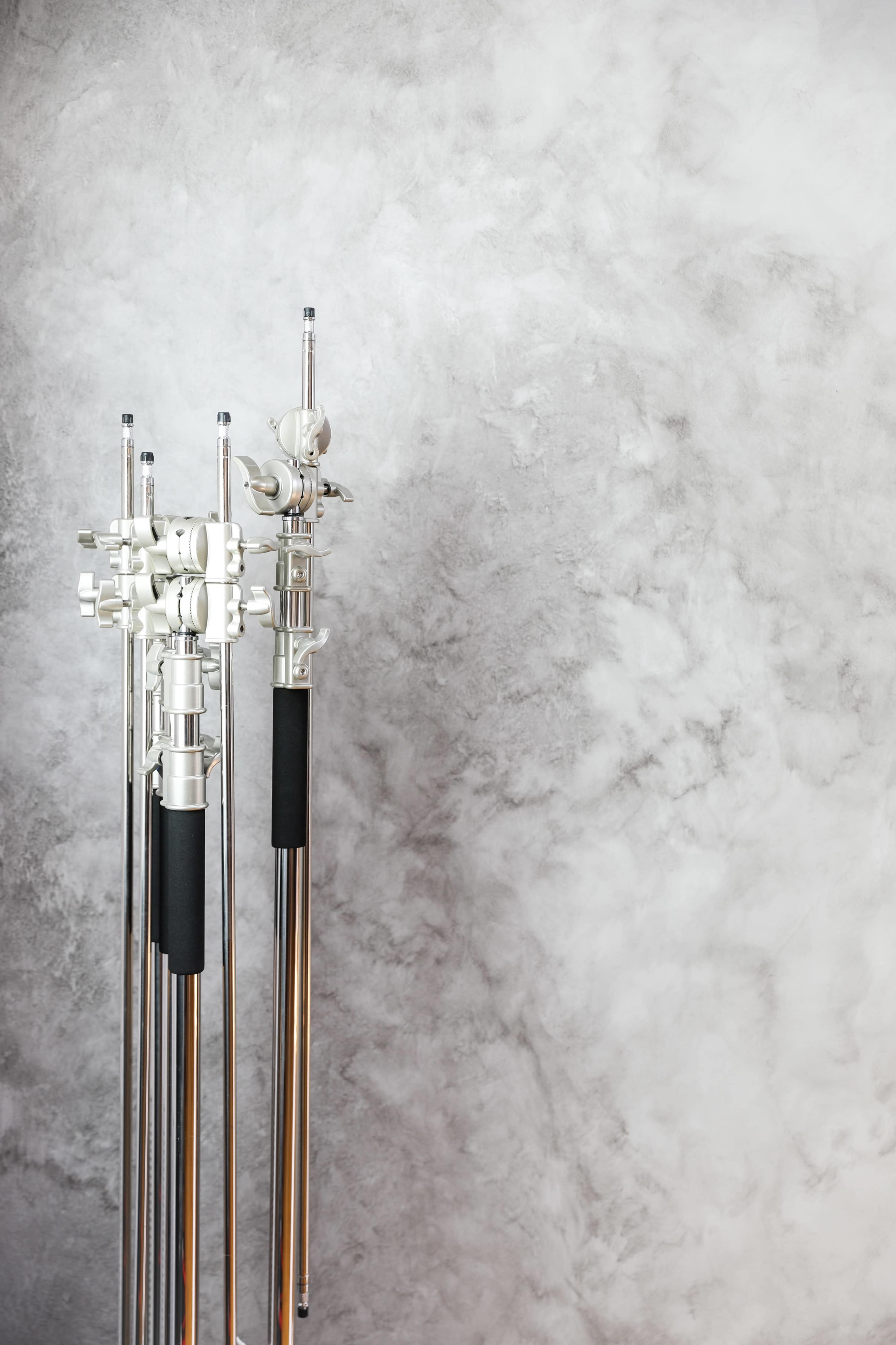 Multiple photo or video light stands positioned against a textured gray wall.
