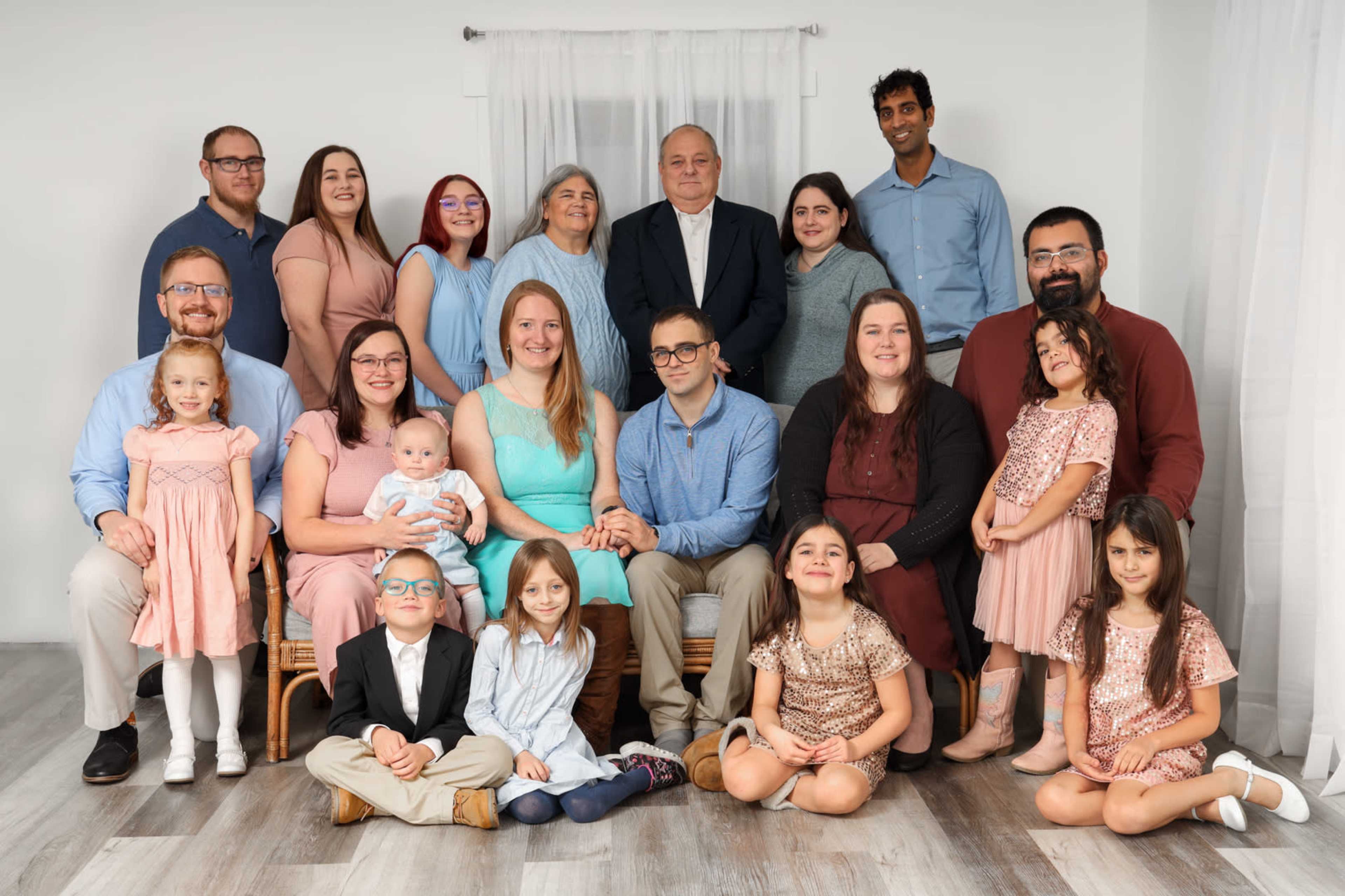 A large family group poses together in a bright indoor setting for a photograph.