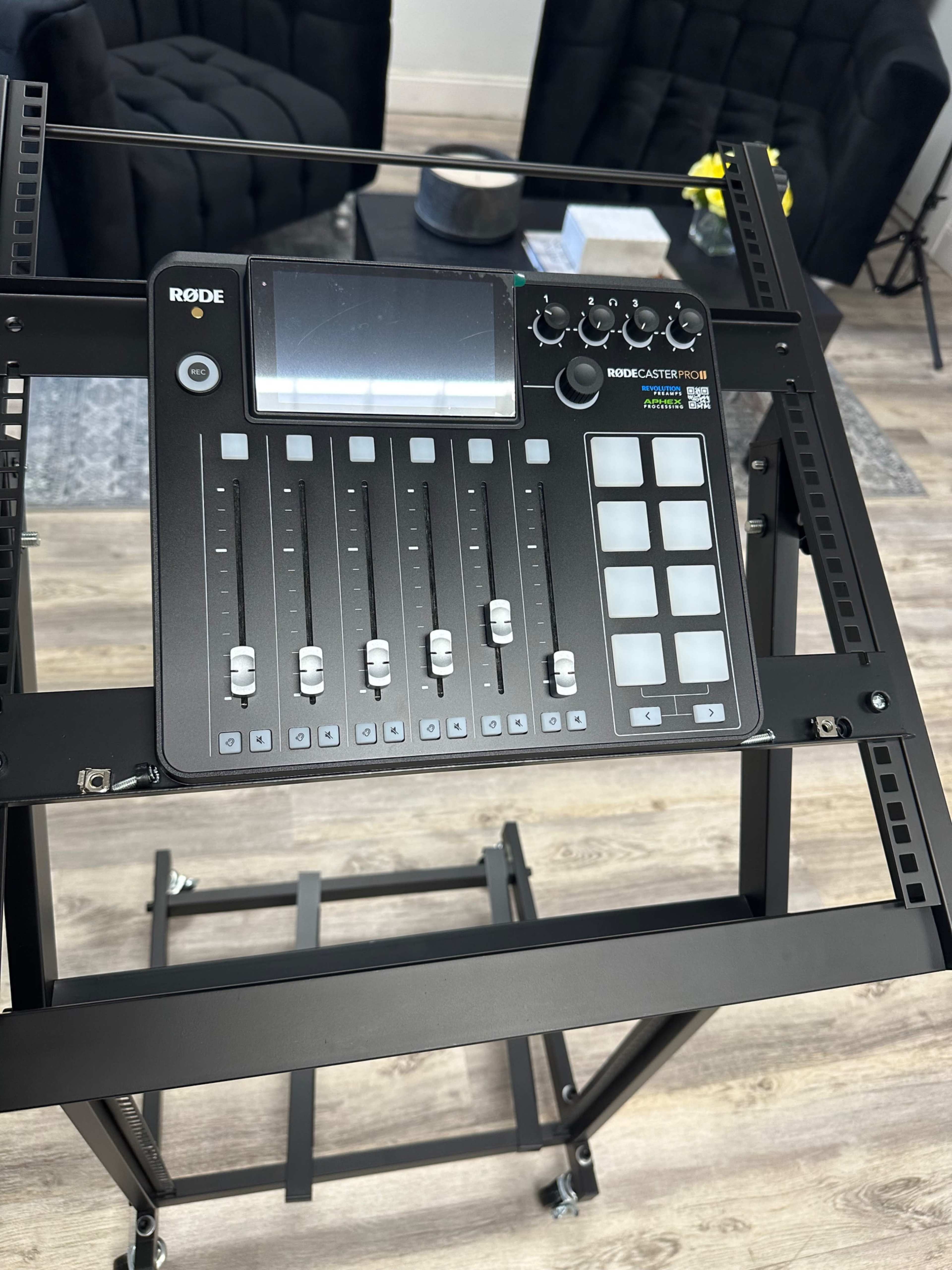 The image shows a Rodecaster Pro audio mixing console placed on a metal equipment rack.