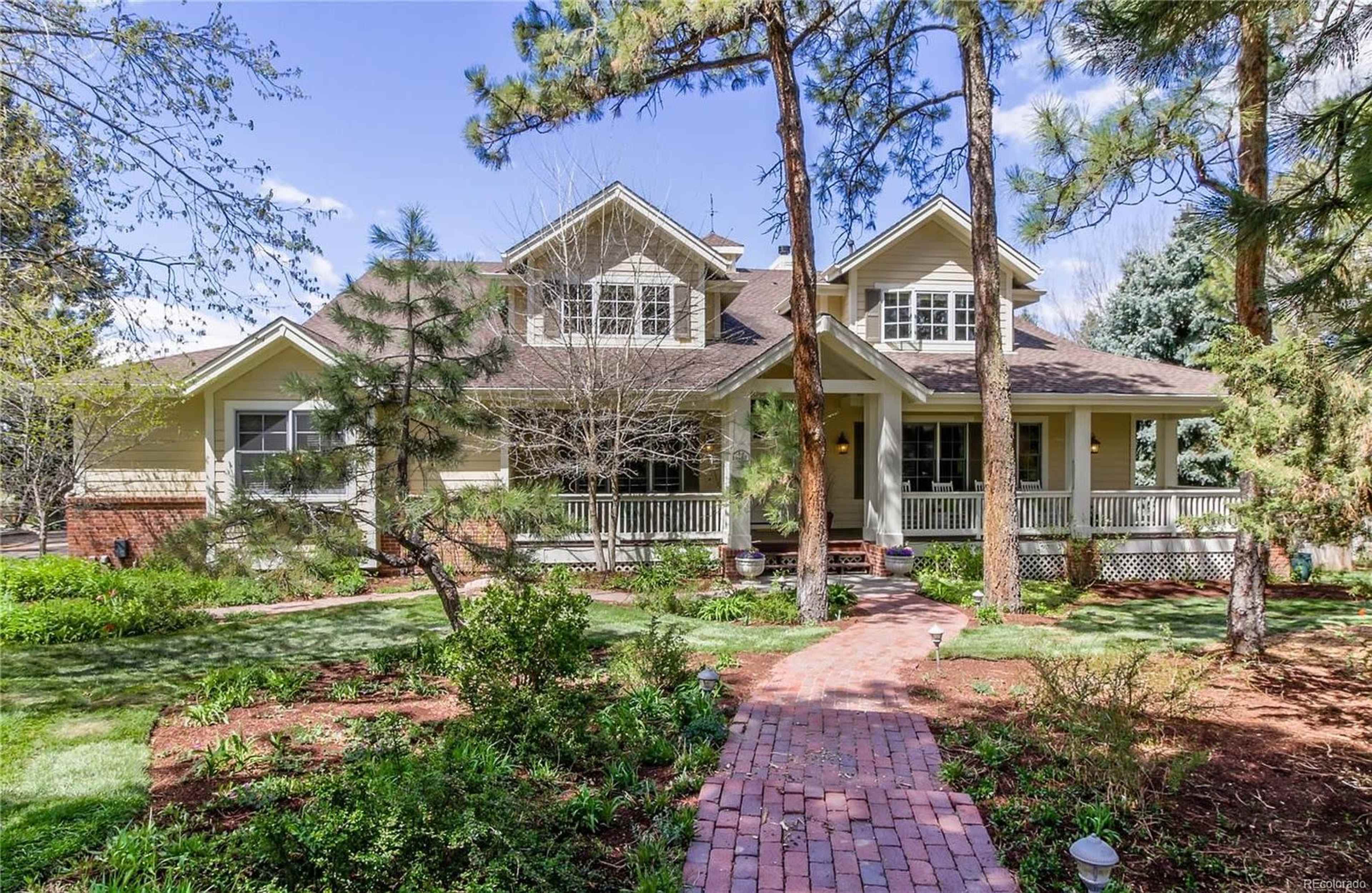 A large, two-story house surrounded by trees and a well-maintained pathway leading to the front porch.