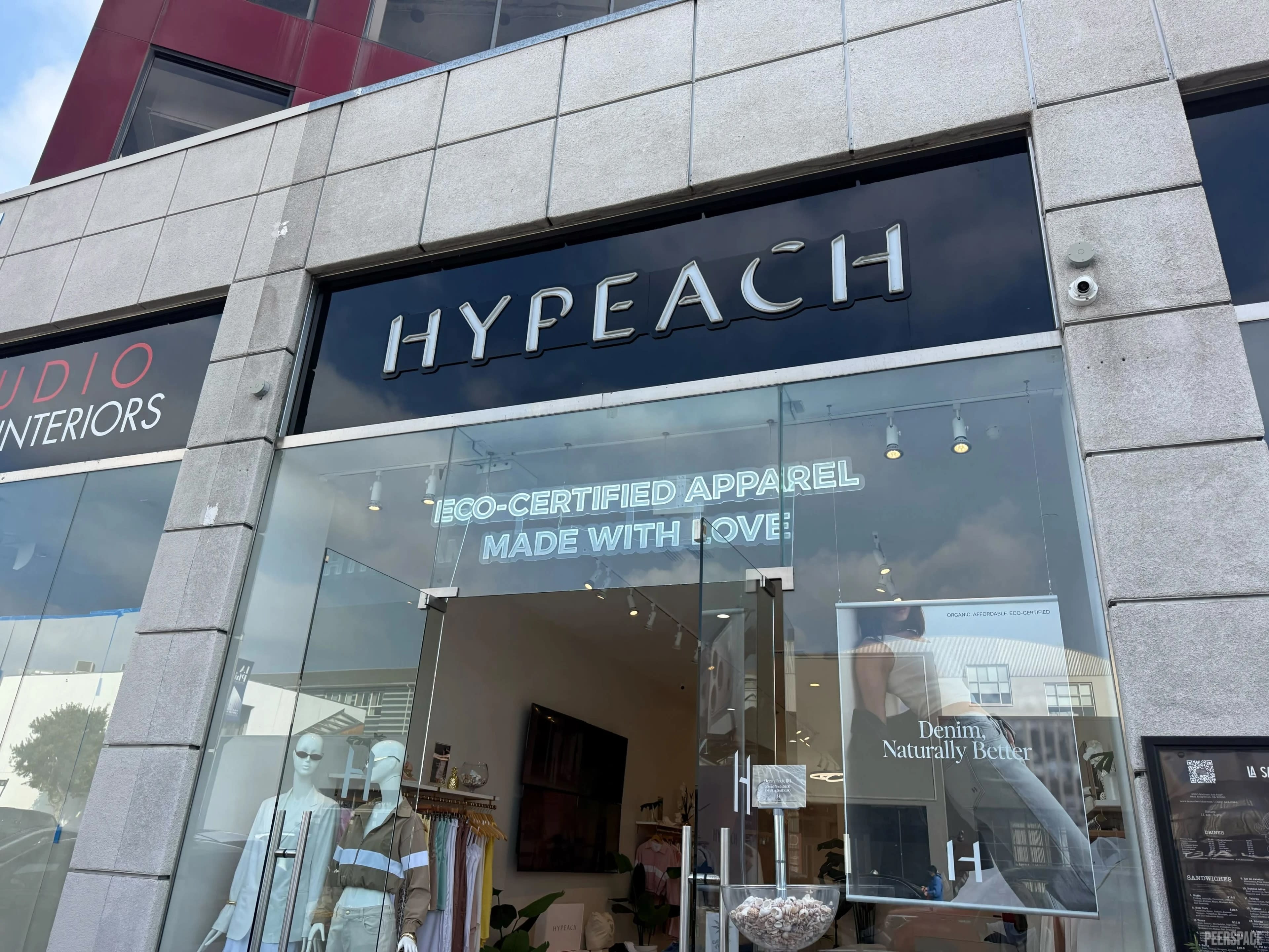 The image shows the storefront of a clothing shop named "Hypeach," featuring a sign that highlights eco-certified apparel.