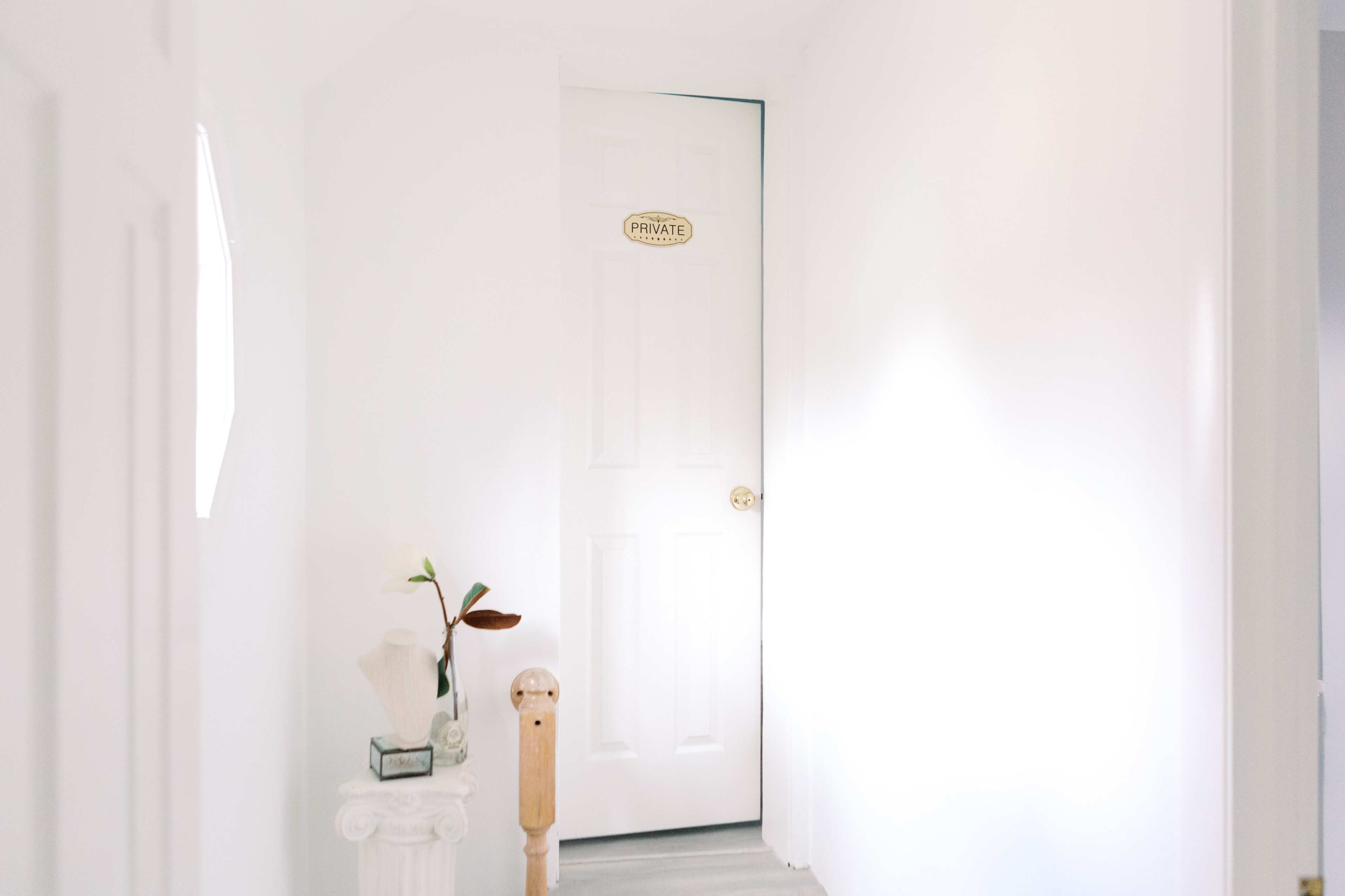 A narrow hallway leads to a closed door labeled "PRIVATE," with a small plant and a decorative column on the side.
