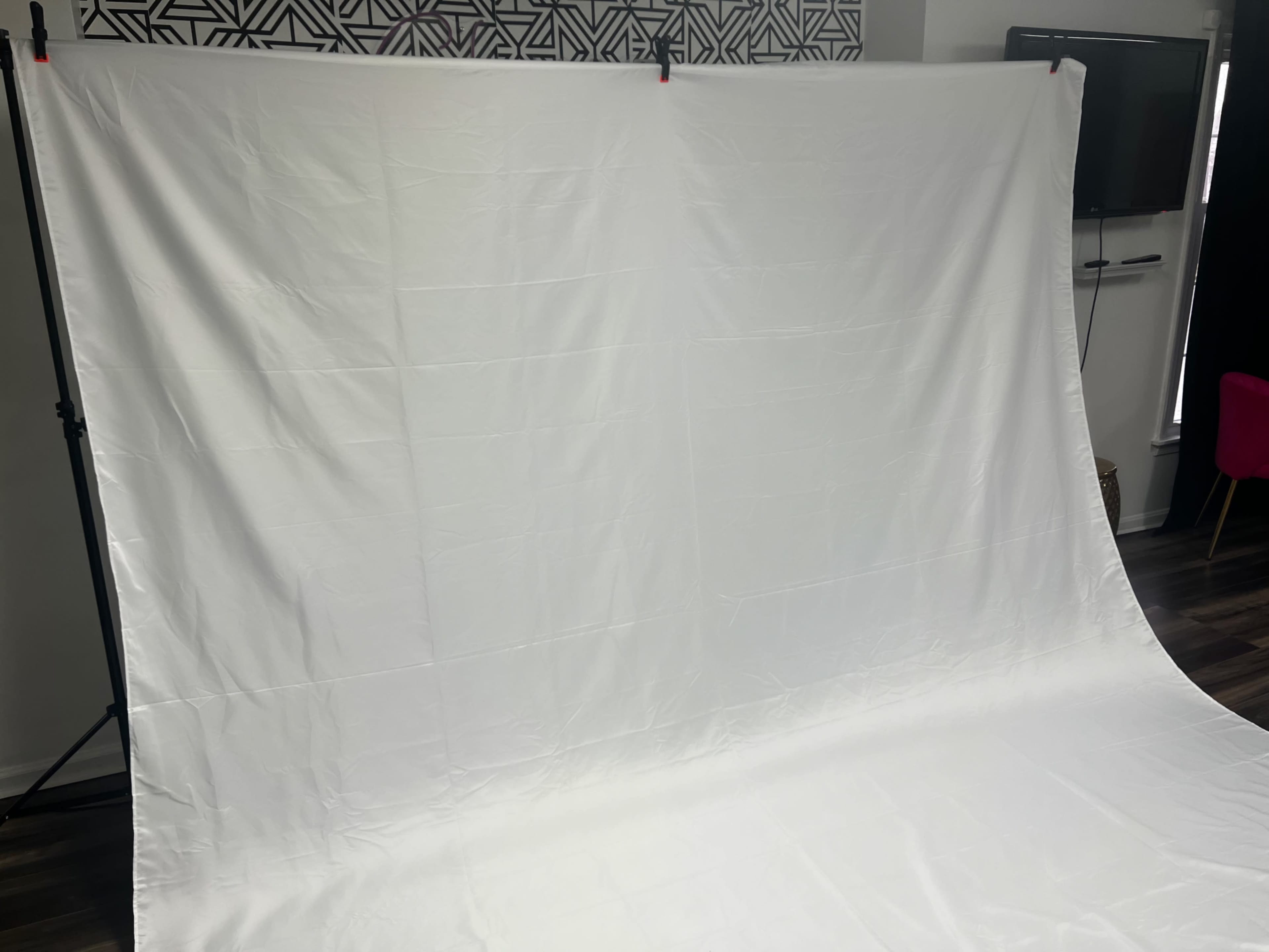 A large white backdrop is set up in a photography studio, extending floor-to-ceiling and covering the floor.