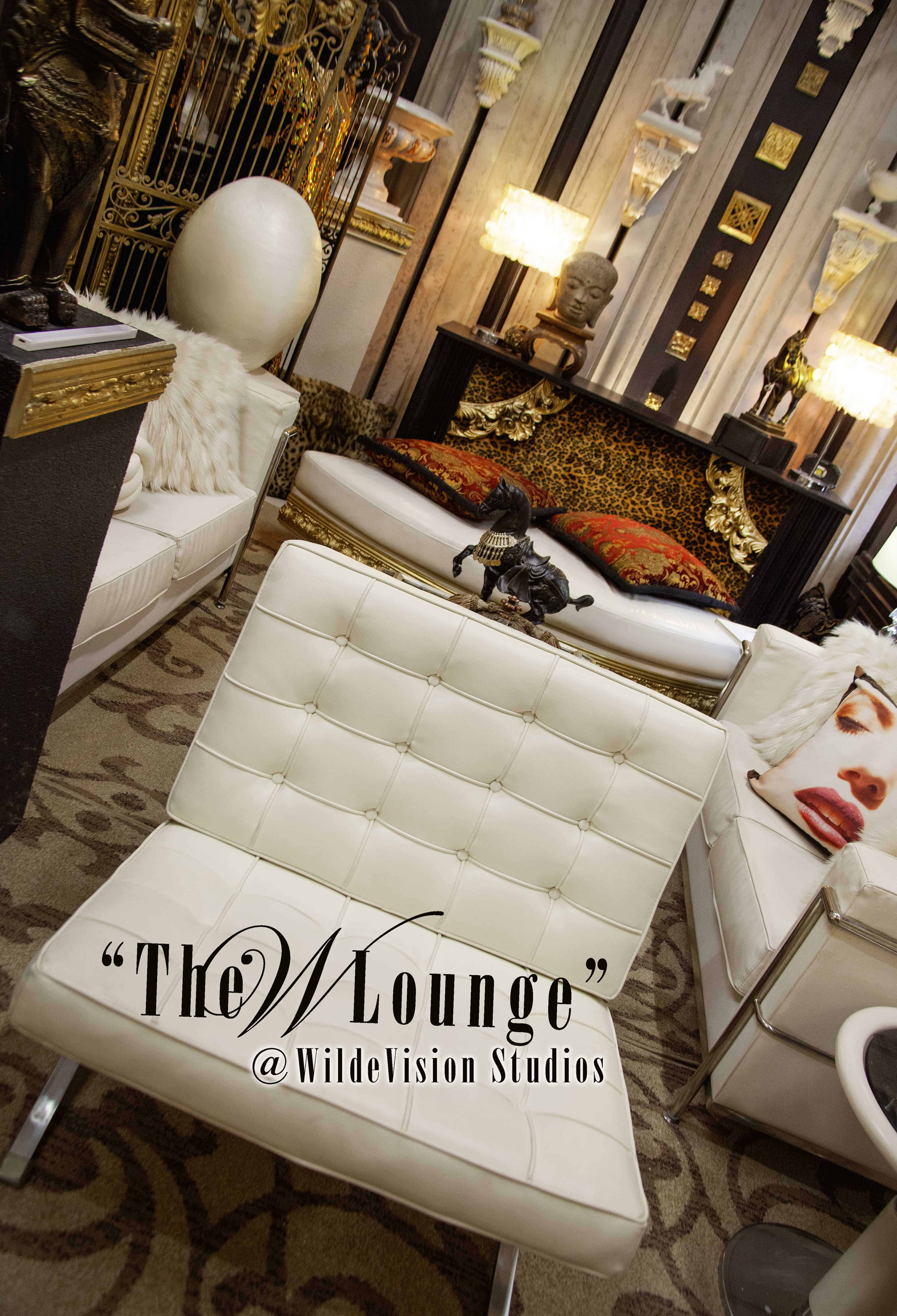 The image shows a modern lounge area featuring white leather furniture, decorative sculptures, and a leopard print accent in a stylish studio setting.