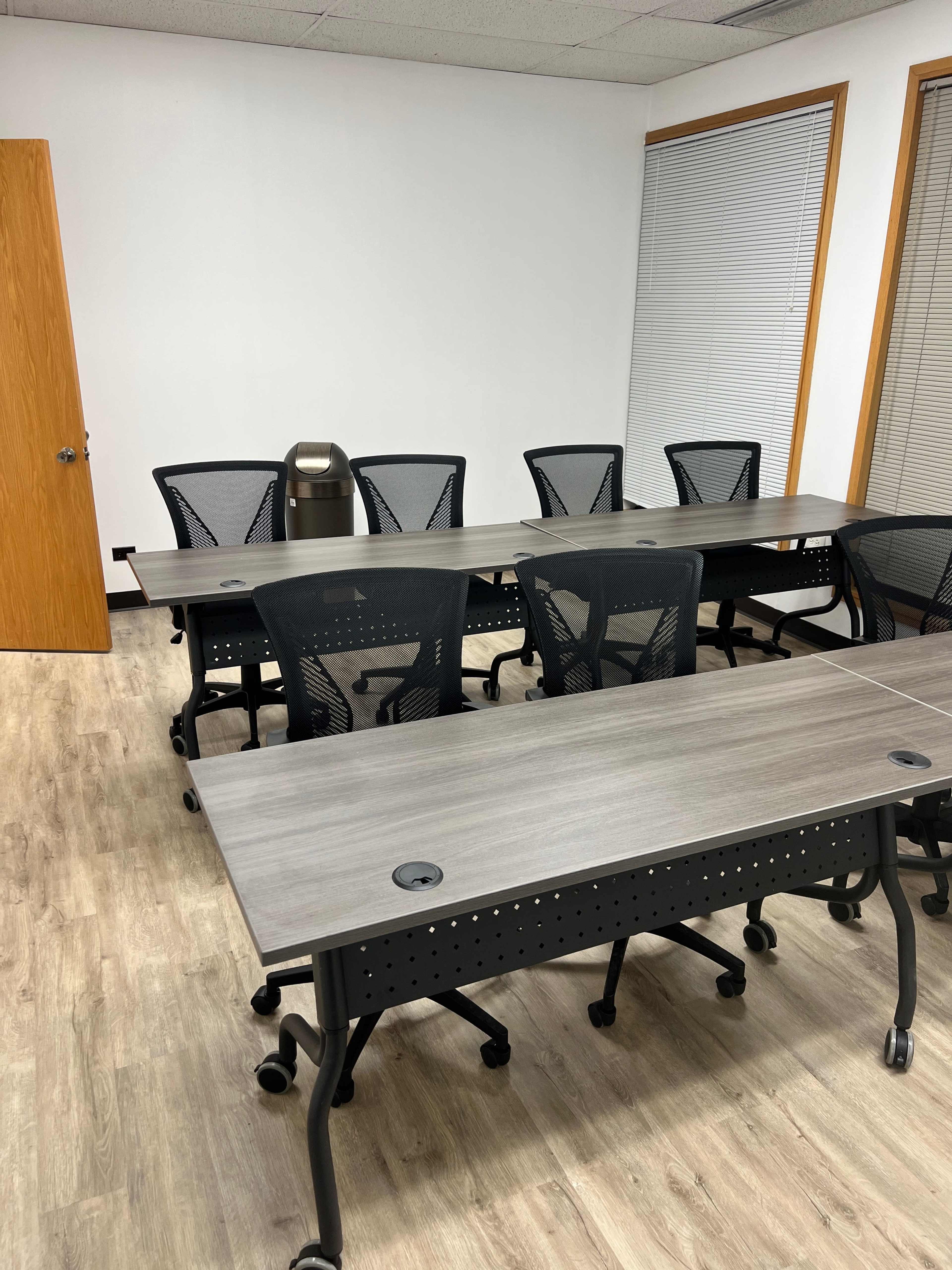 A modern conference room with a long table and several black mesh chairs arranged around it.