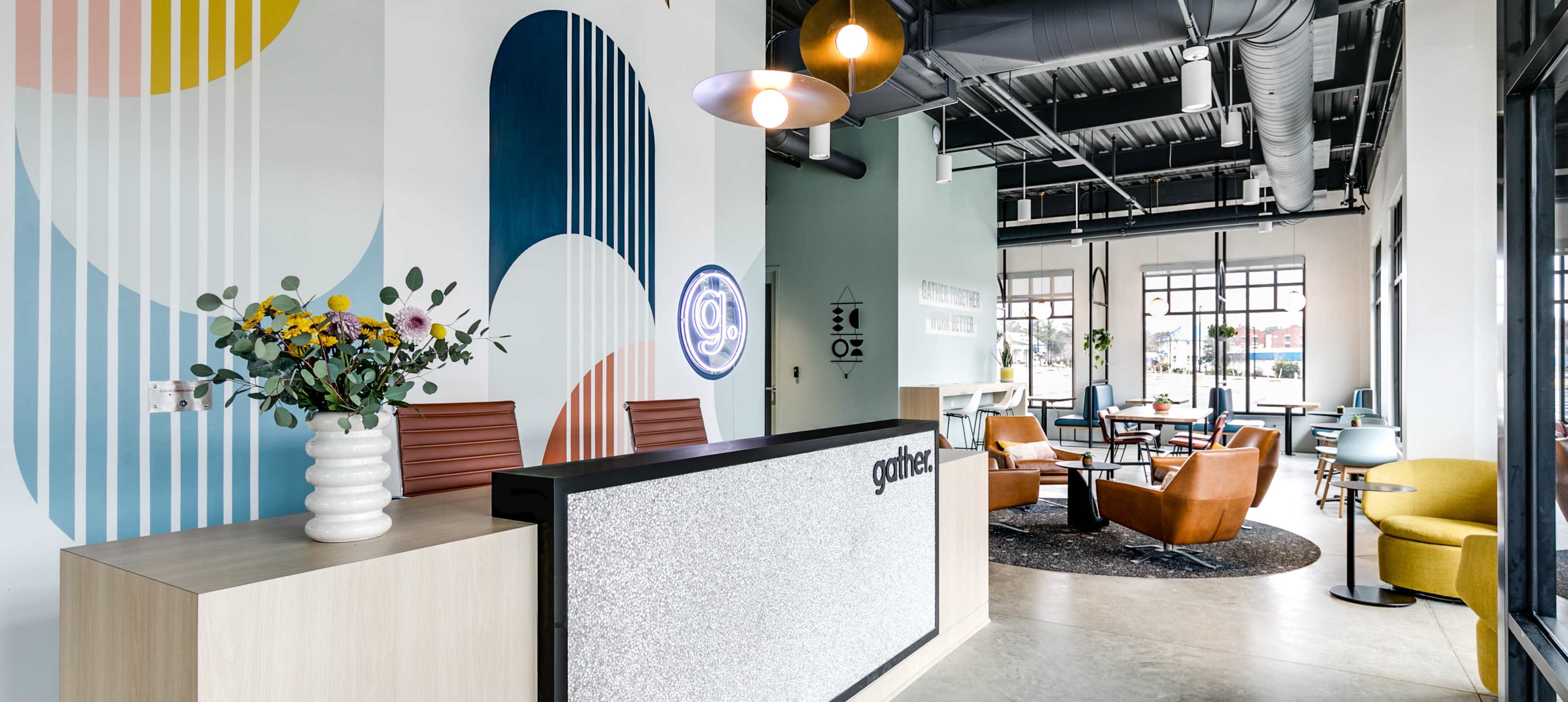 A modern reception area featuring a desk adorned with decor, colorful wall patterns, and various seating arrangements with plants.
