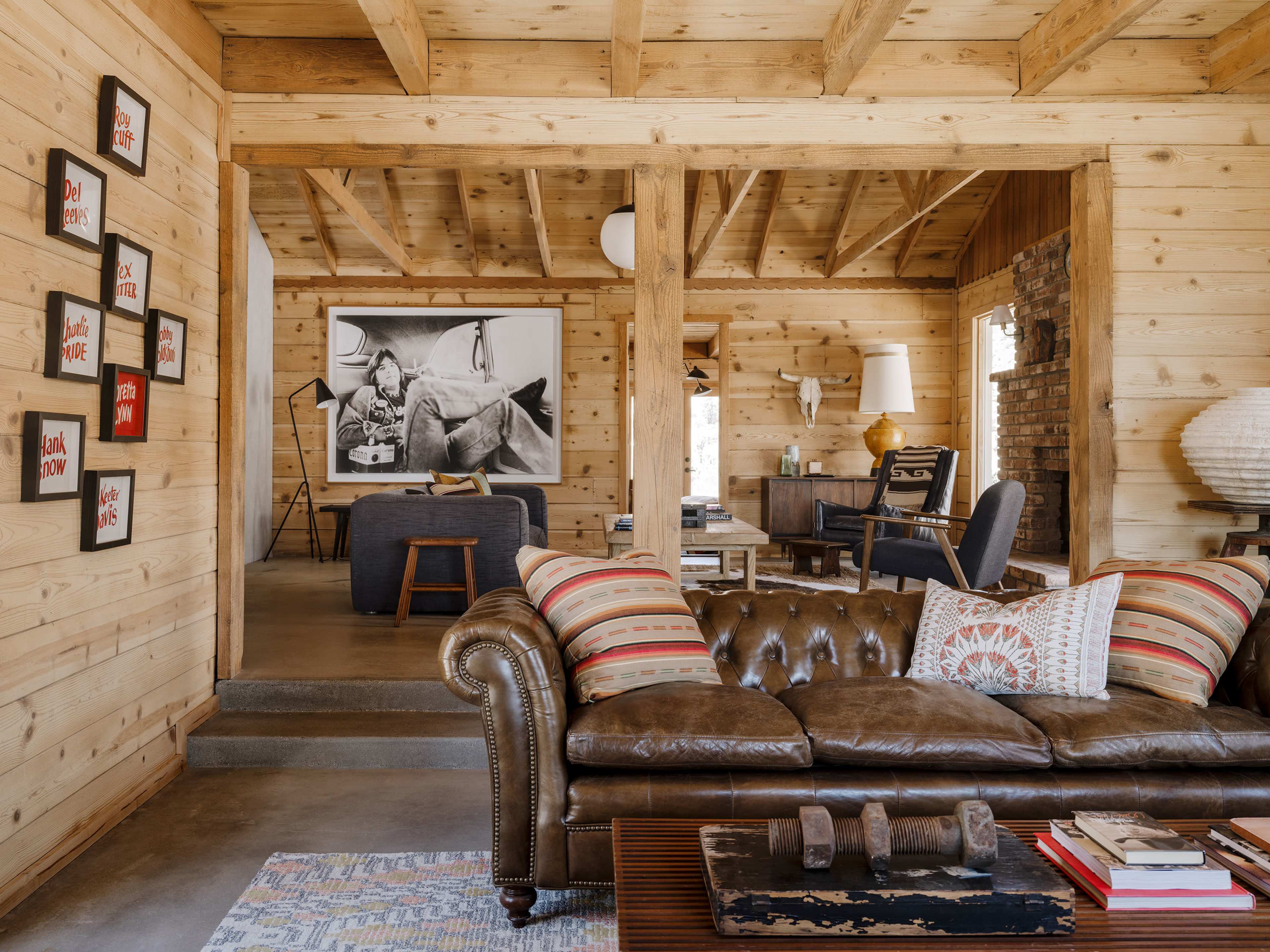 A rustic living room with wooden walls, a leather couch, and a large black-and-white photograph on the wall.