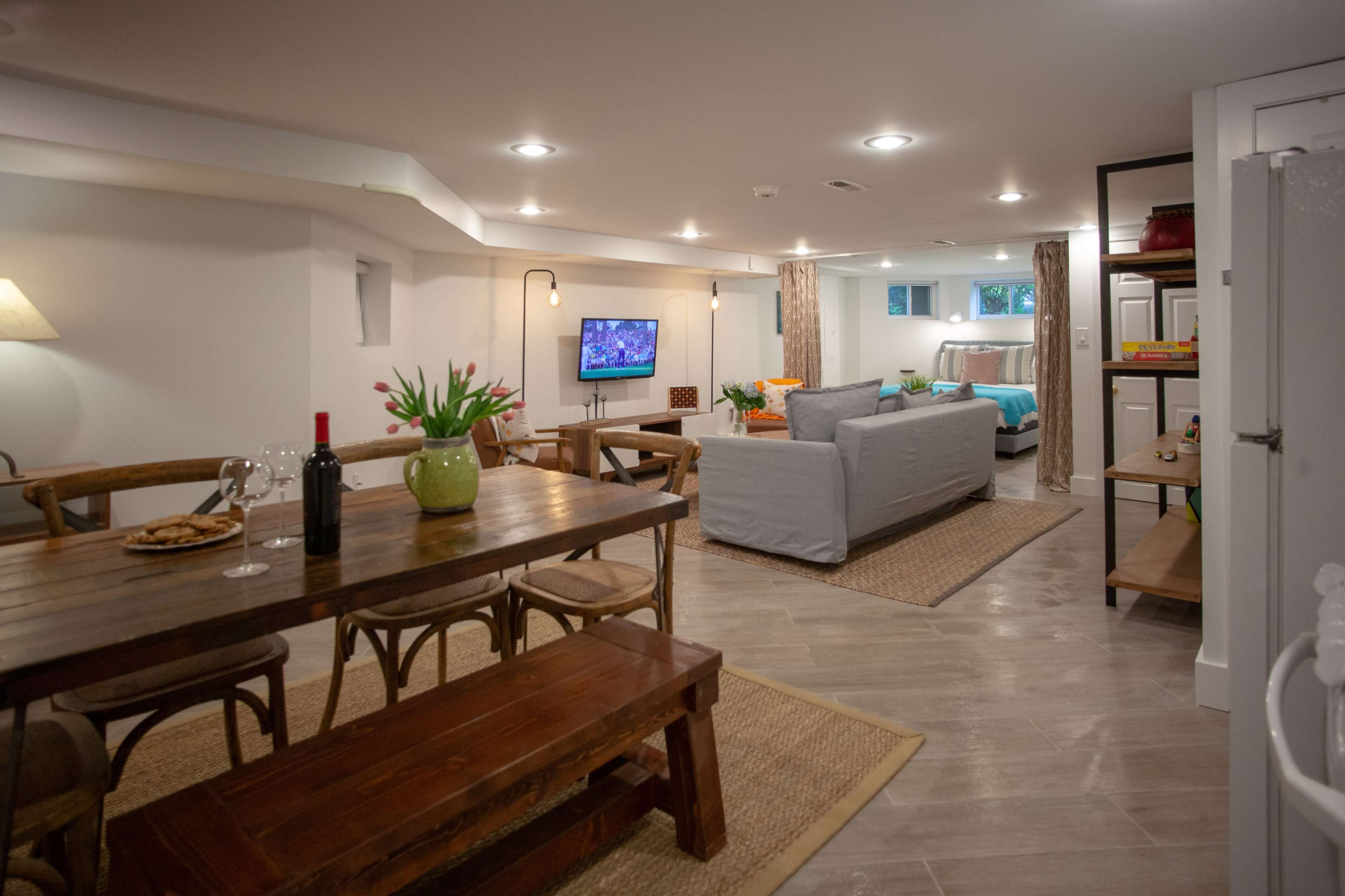 A spacious basement area features a dining table, a living space with a television, and a well-decorated seating area.