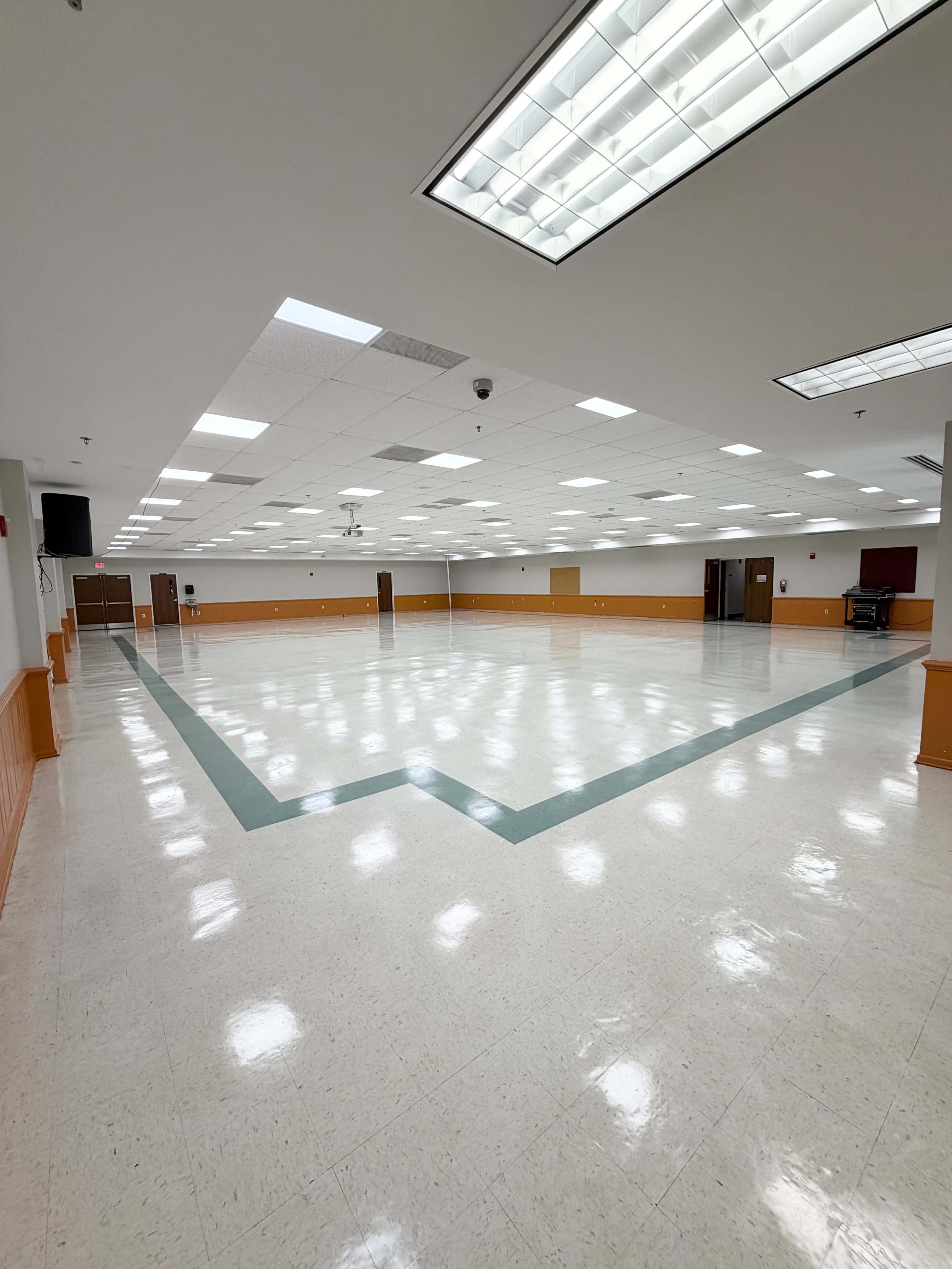 The image shows a large, empty hall with a glossy floor and a green outline along the perimeter.
