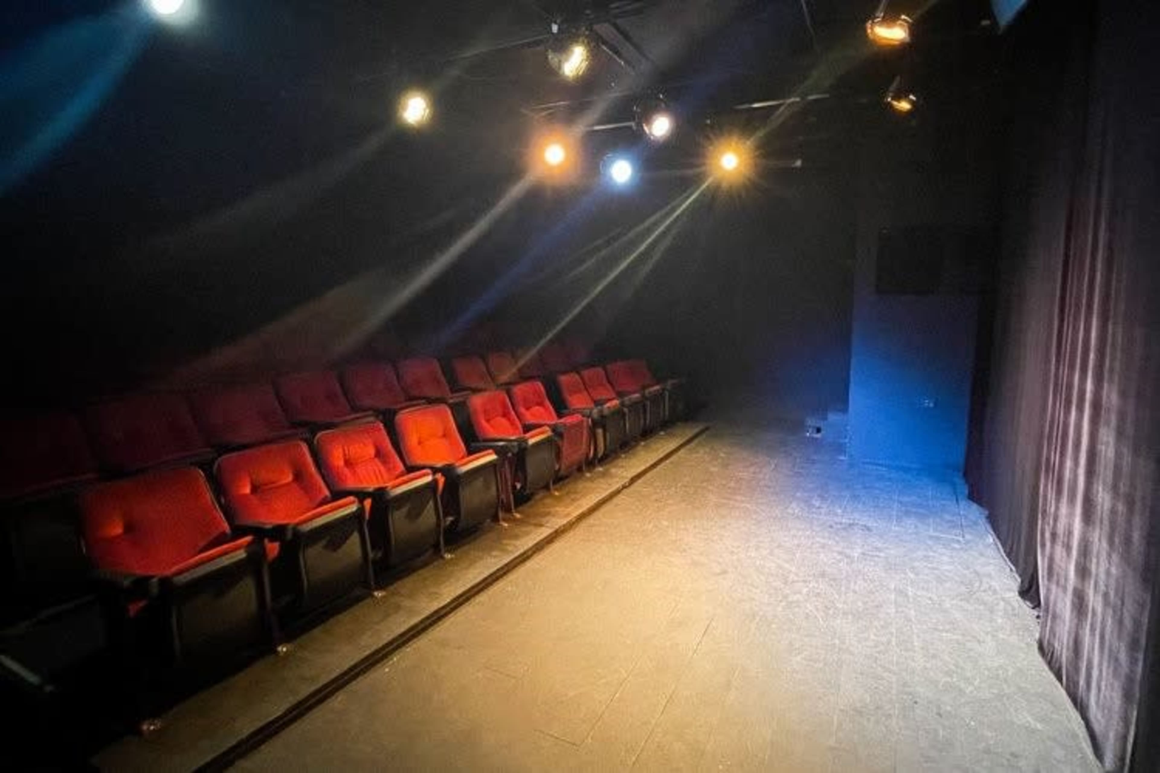 A small theater space with red seats arranged in rows and dim lighting.