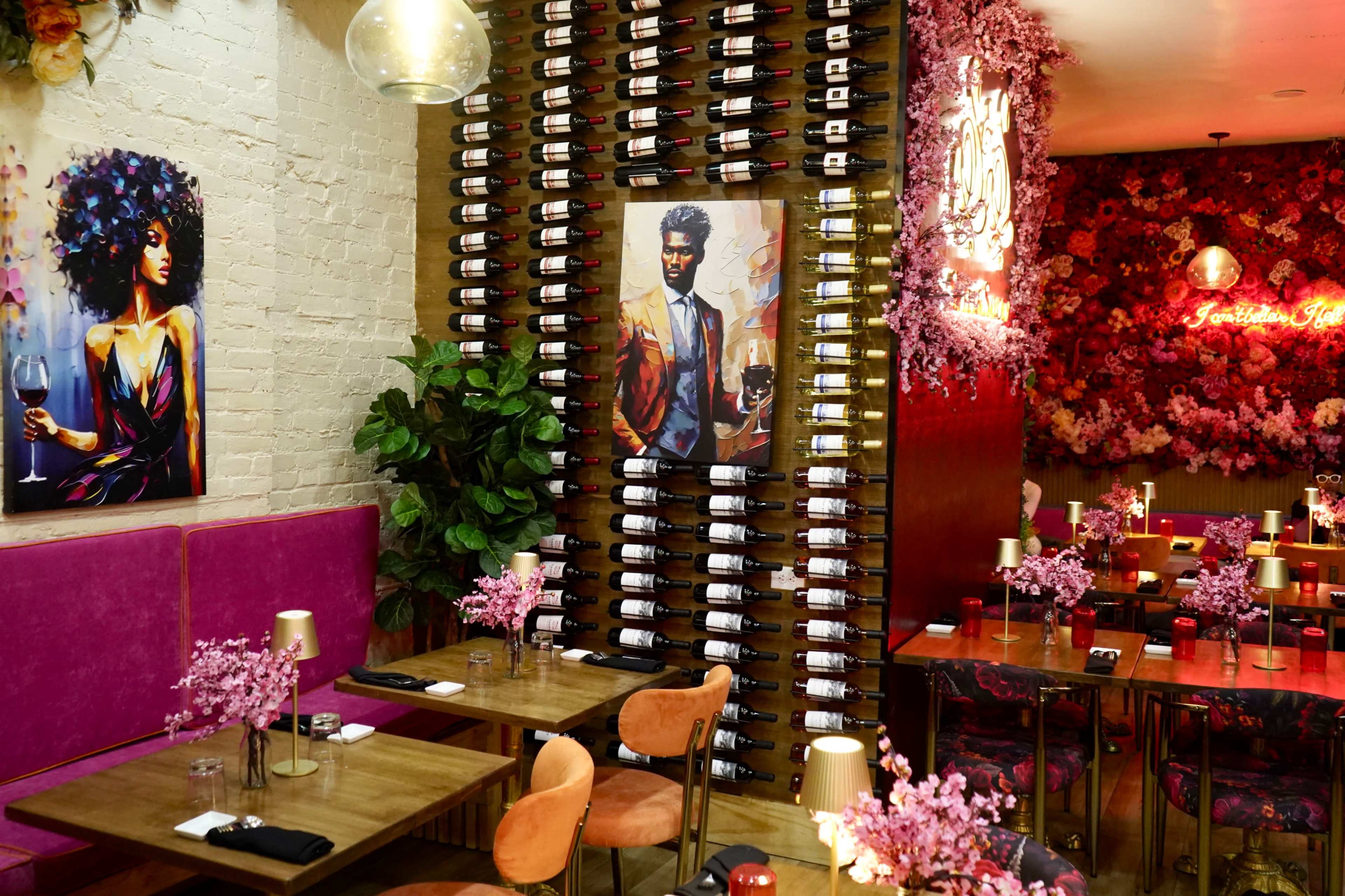 The image shows a stylish restaurant interior with a wine rack on the wall, floral decor, and tables set for dining.