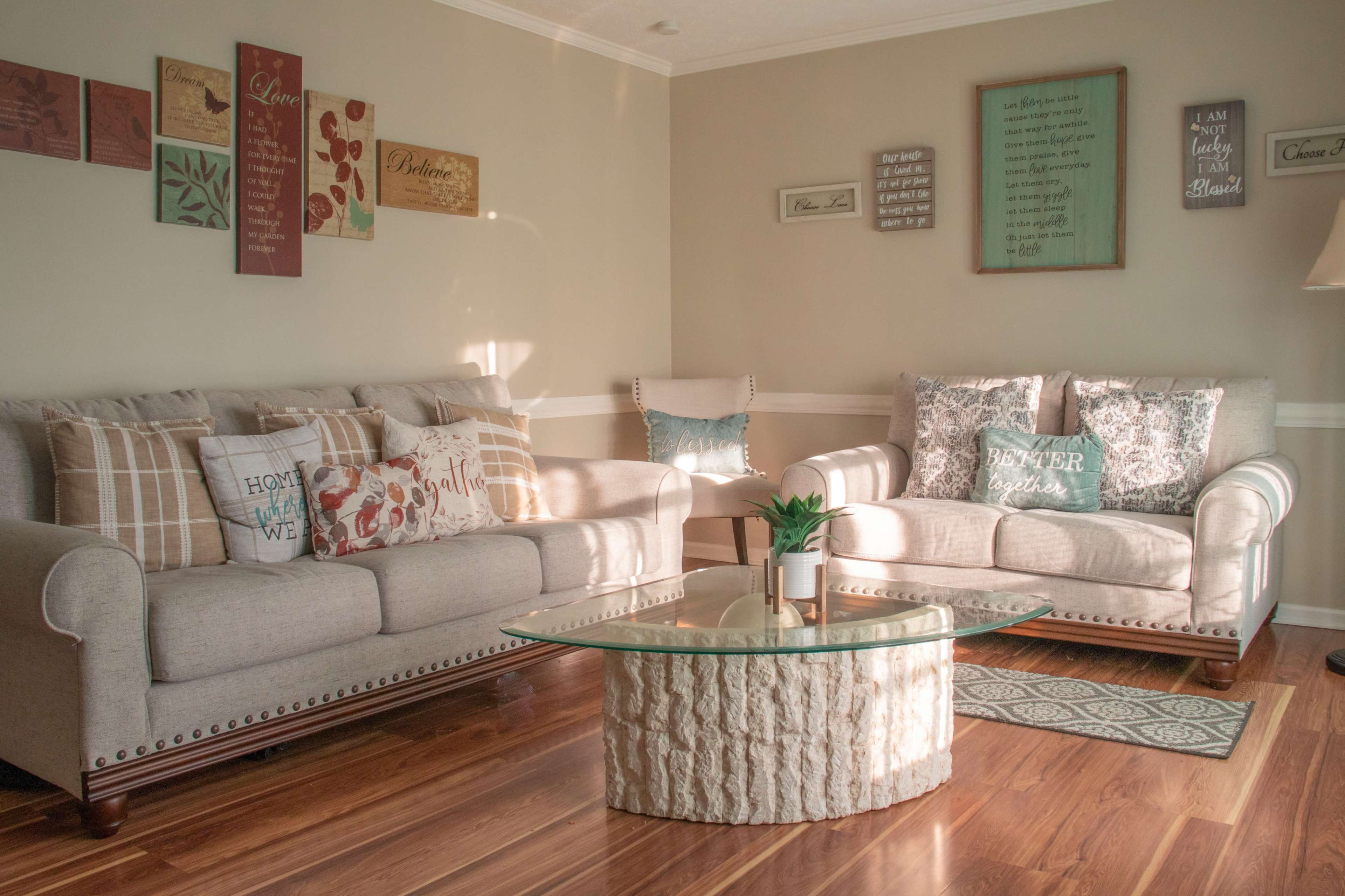A cozy living room with two beige couches, a glass coffee table, and decorative wall art.