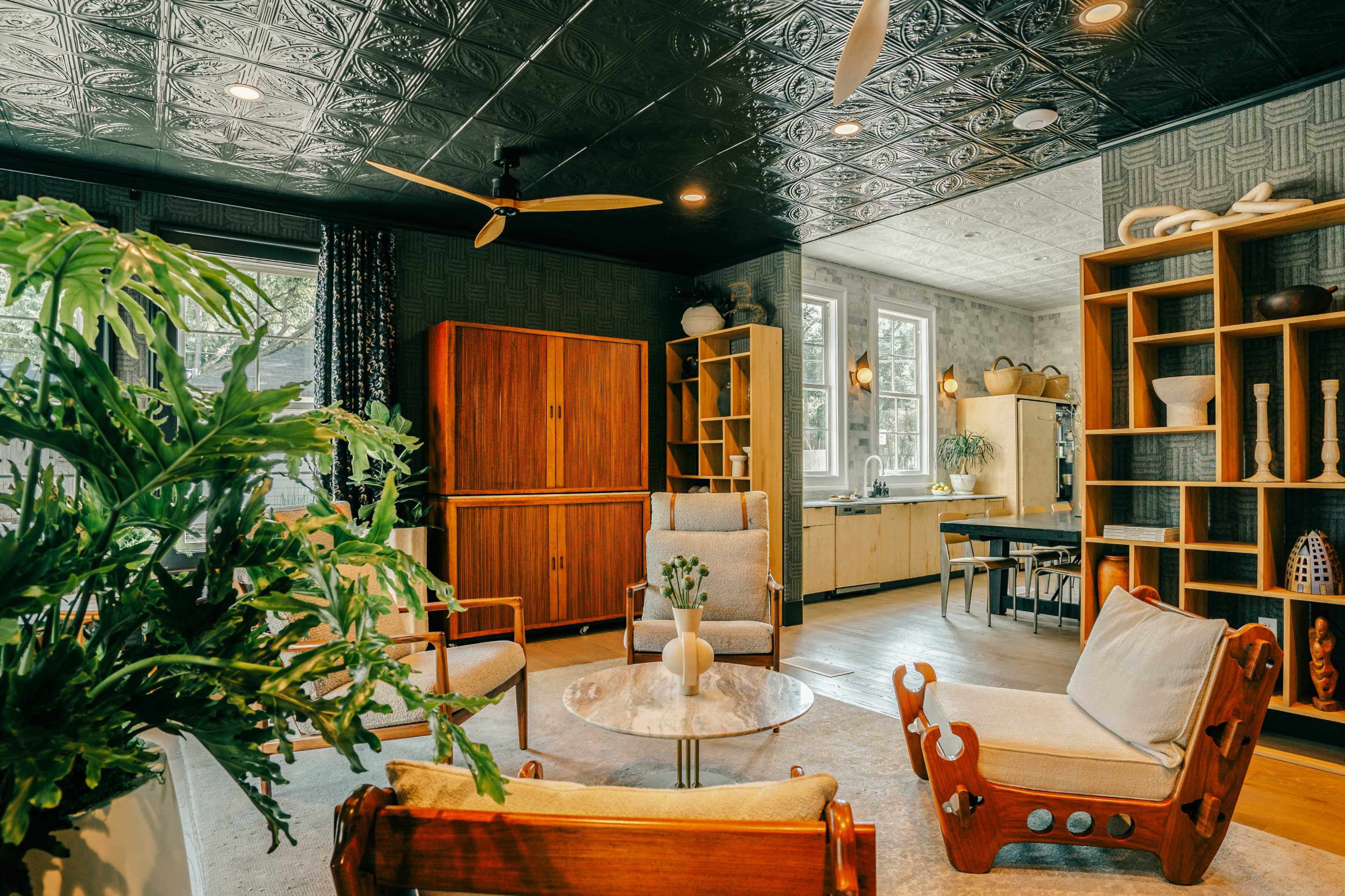 The image depicts a stylish living space featuring wooden furniture, a round marble coffee table, and large windows that allow natural light to fill the room.