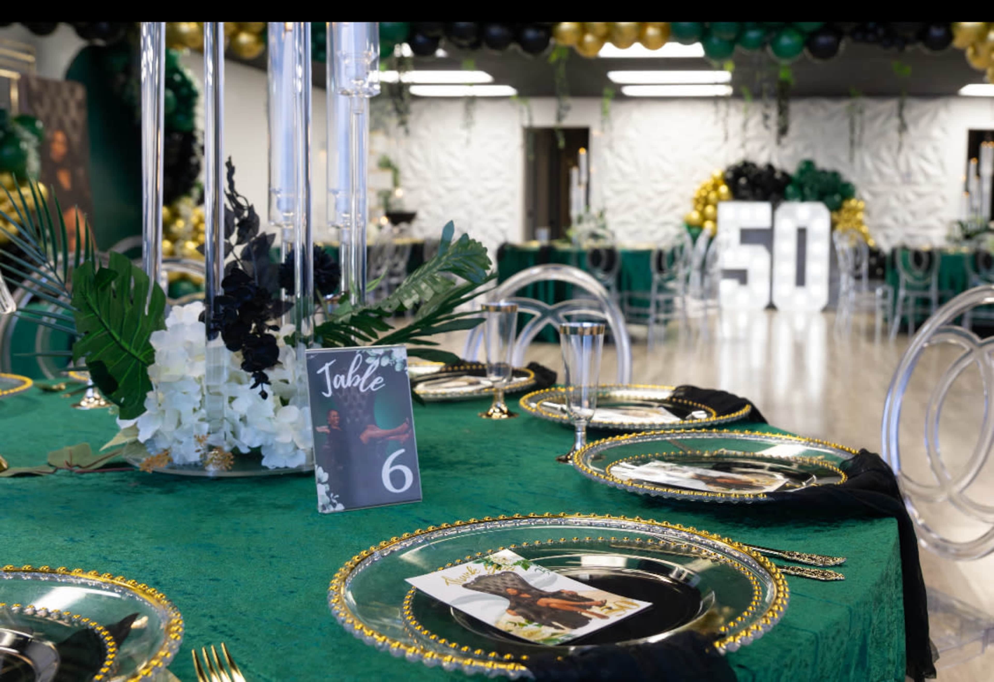 The image shows a banquet setup with an elegant green tablecloth, decorative place settings, and a large "50" display in the background, suggesting a celebratory event.