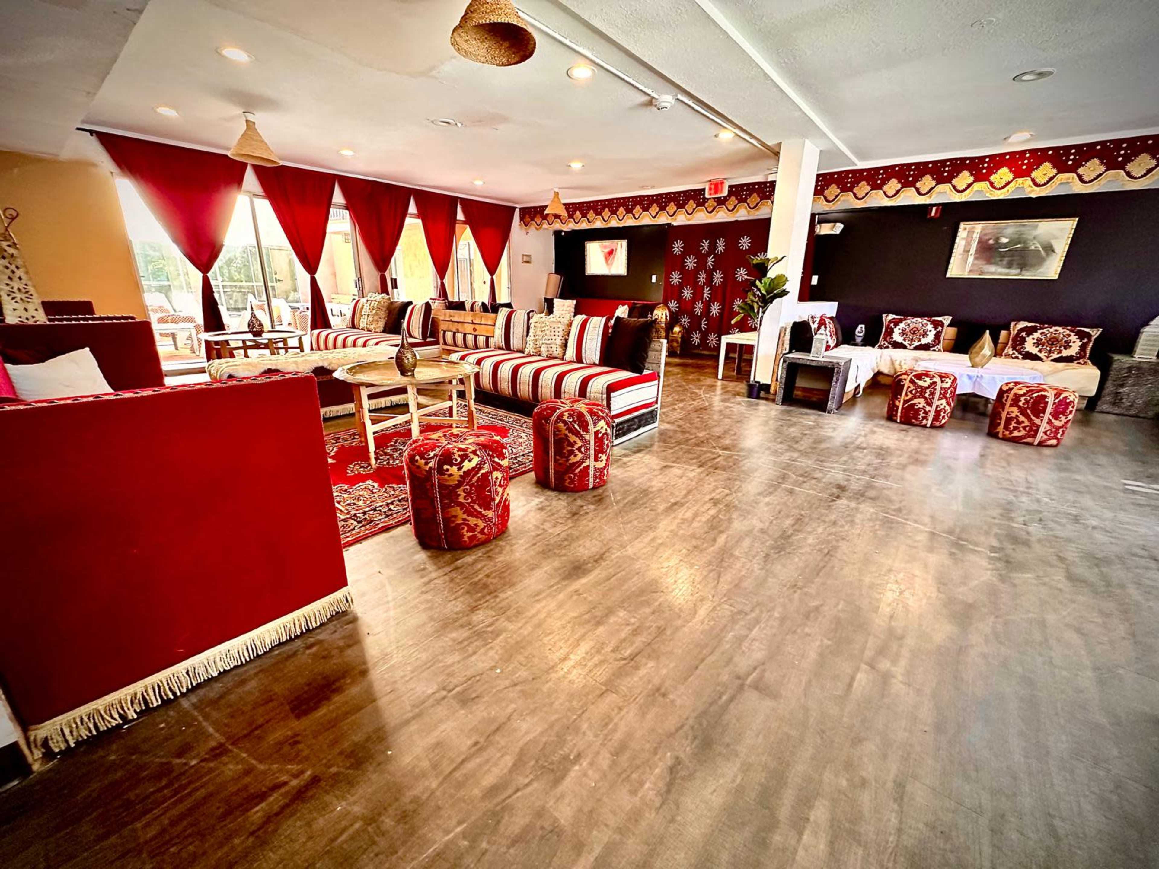 The image shows a spacious indoor lounge area with colorful seating, decorative elements, and large windows letting in natural light.