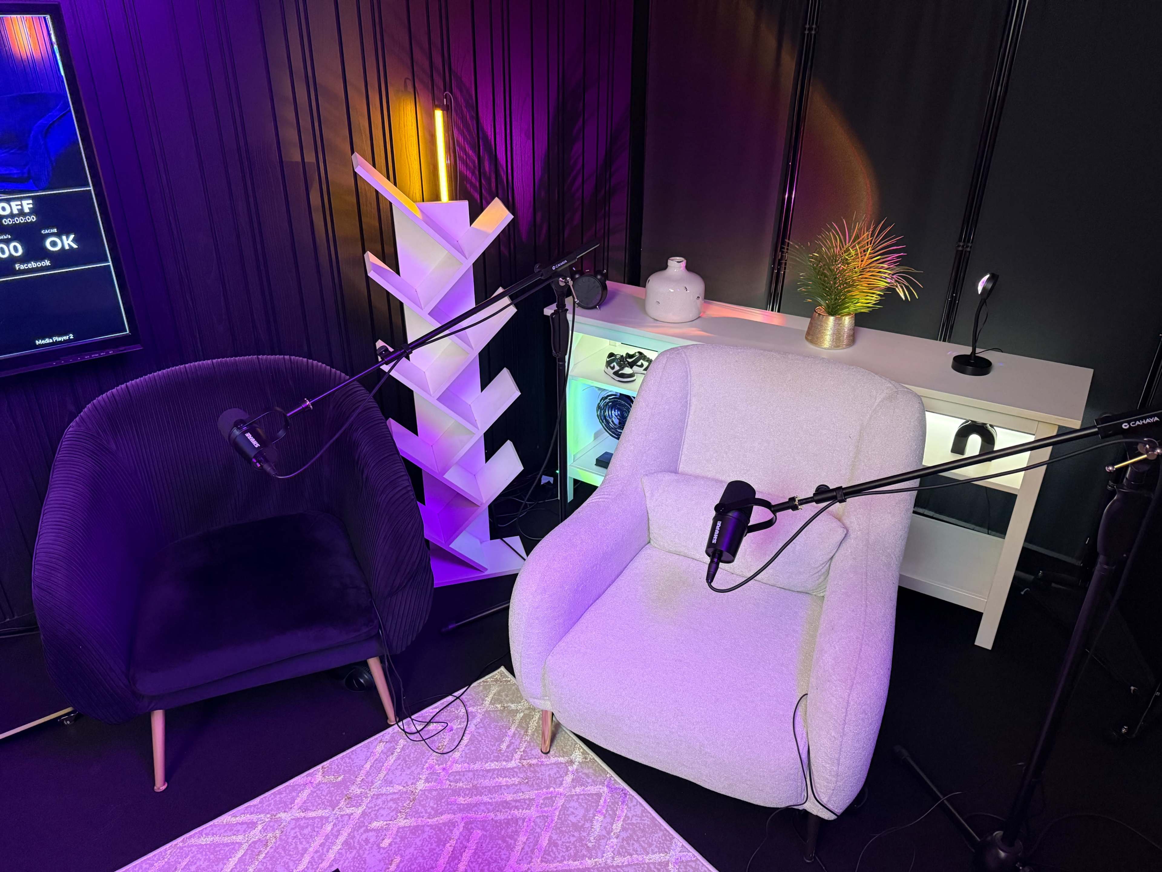 The image shows two cozy chairs with microphones set up in a studio-like environment, accompanied by modern decor and lighting.
