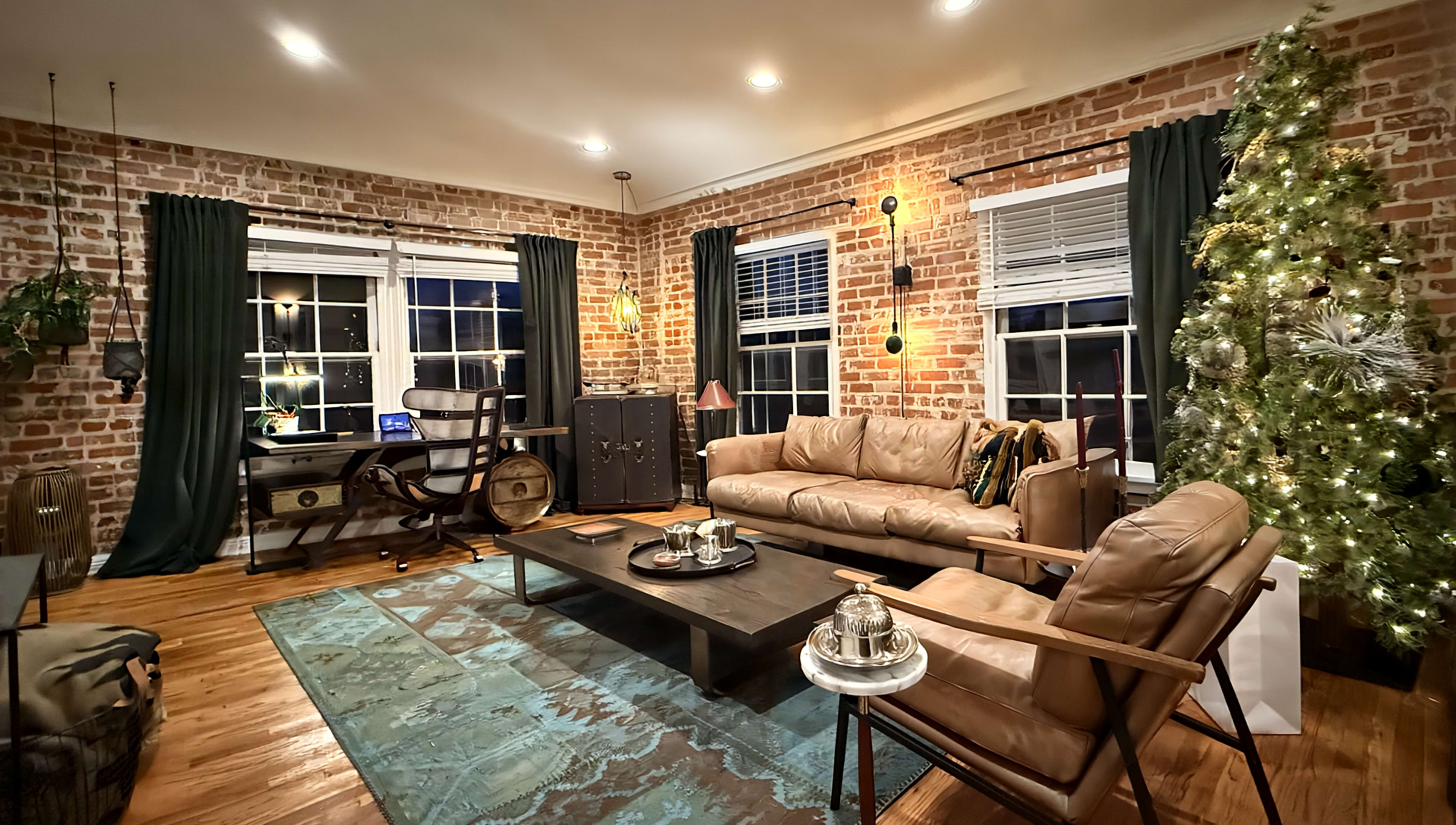 The living room features exposed brick walls, large windows, a Christmas tree, and a mix of modern and vintage furniture.