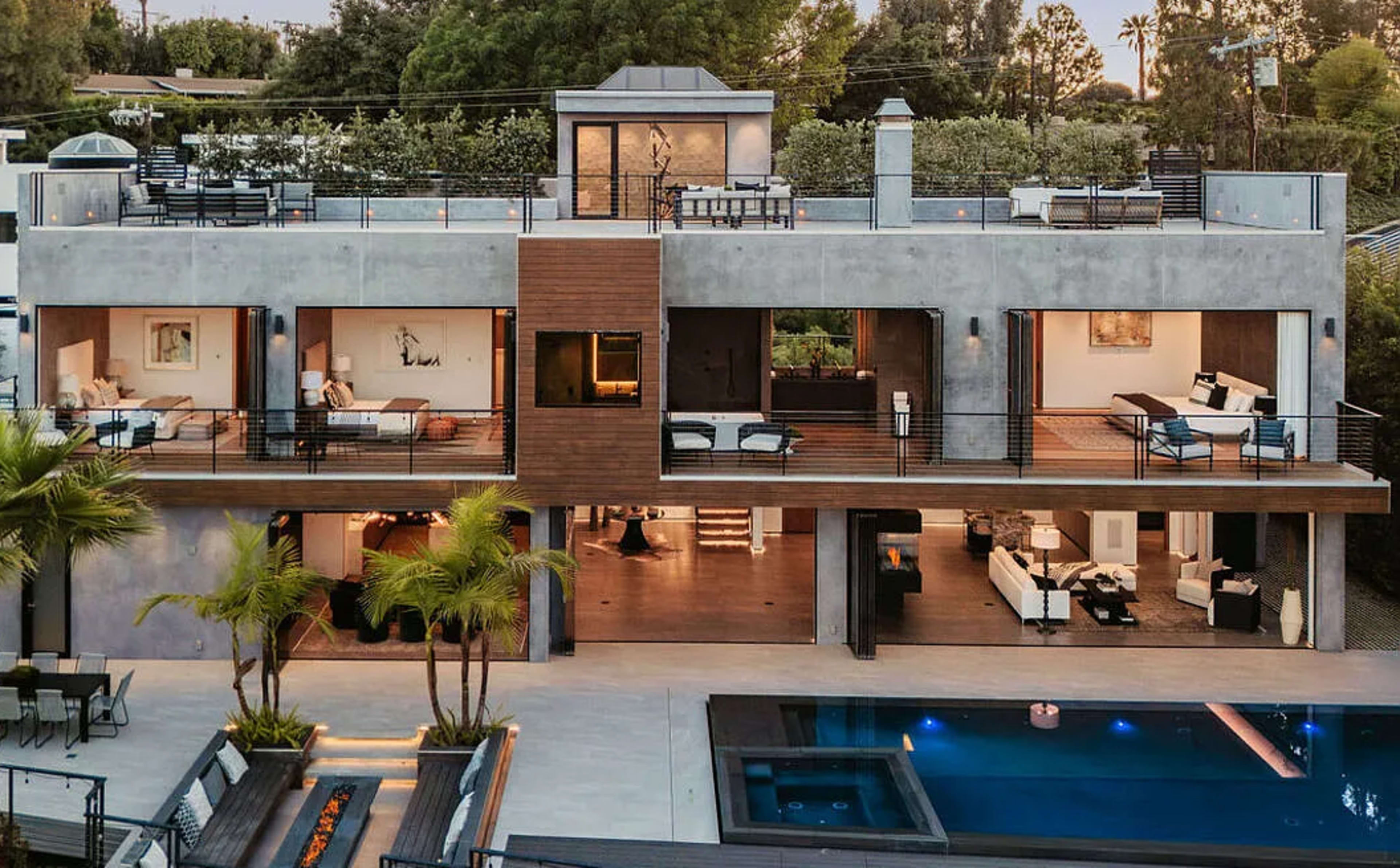 The image shows a modern two-story house with large balconies, an outdoor pool, and a landscaped garden.