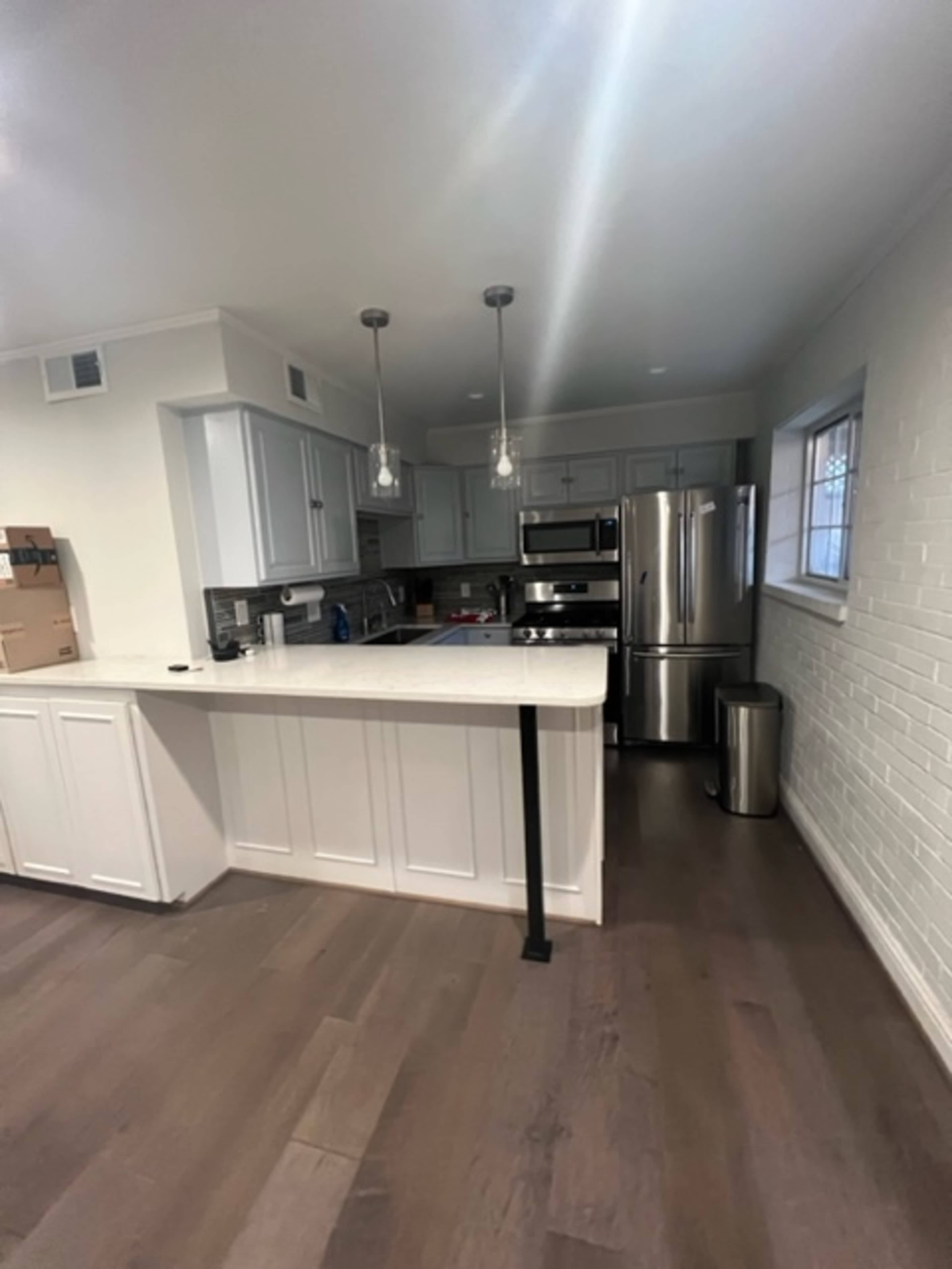 A modern kitchen with white cabinetry, stainless steel appliances, and a central island with pendant lighting.