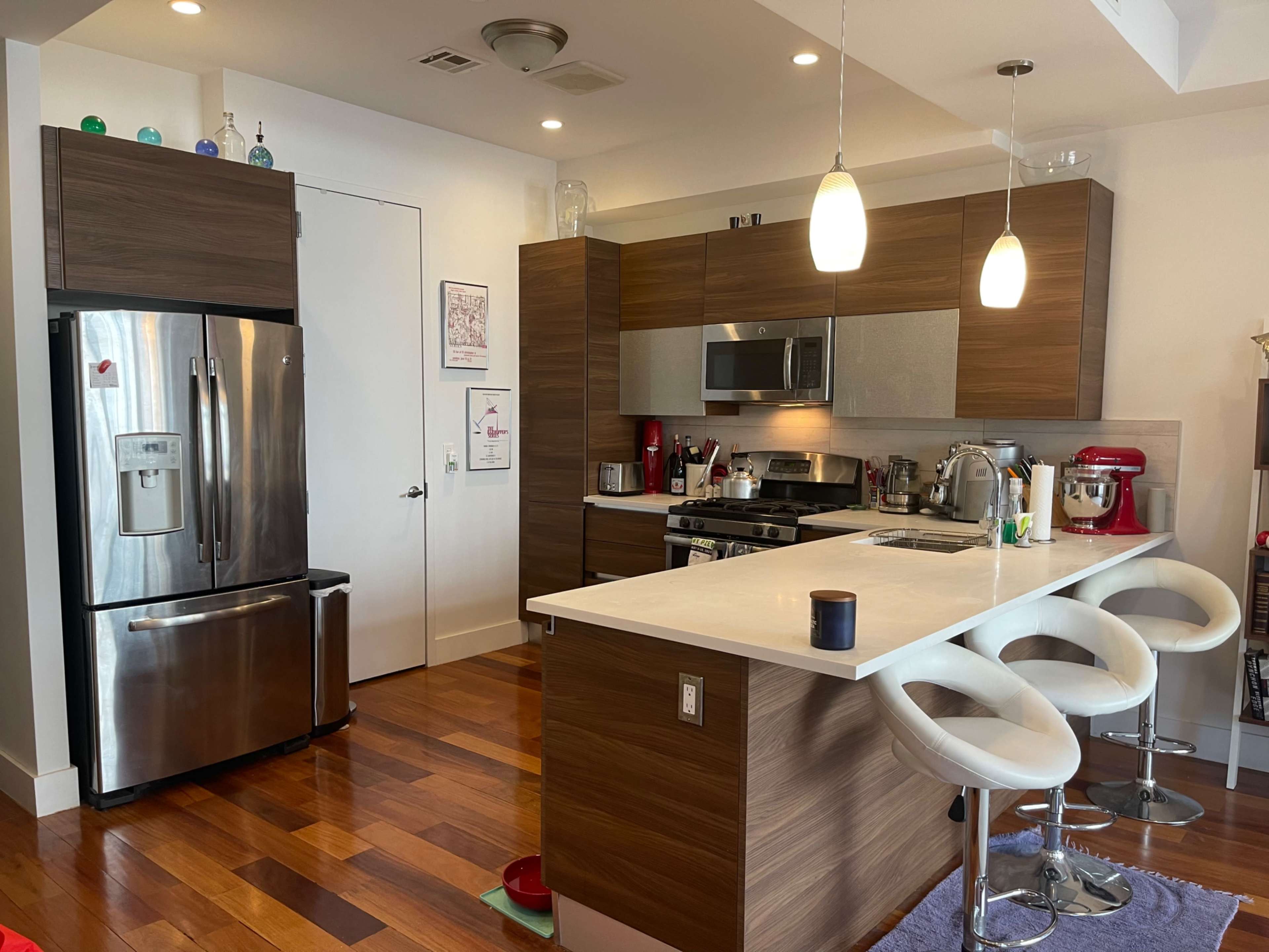 A modern kitchen features stainless steel appliances, wooden cabinetry, and a central island with bar stools.