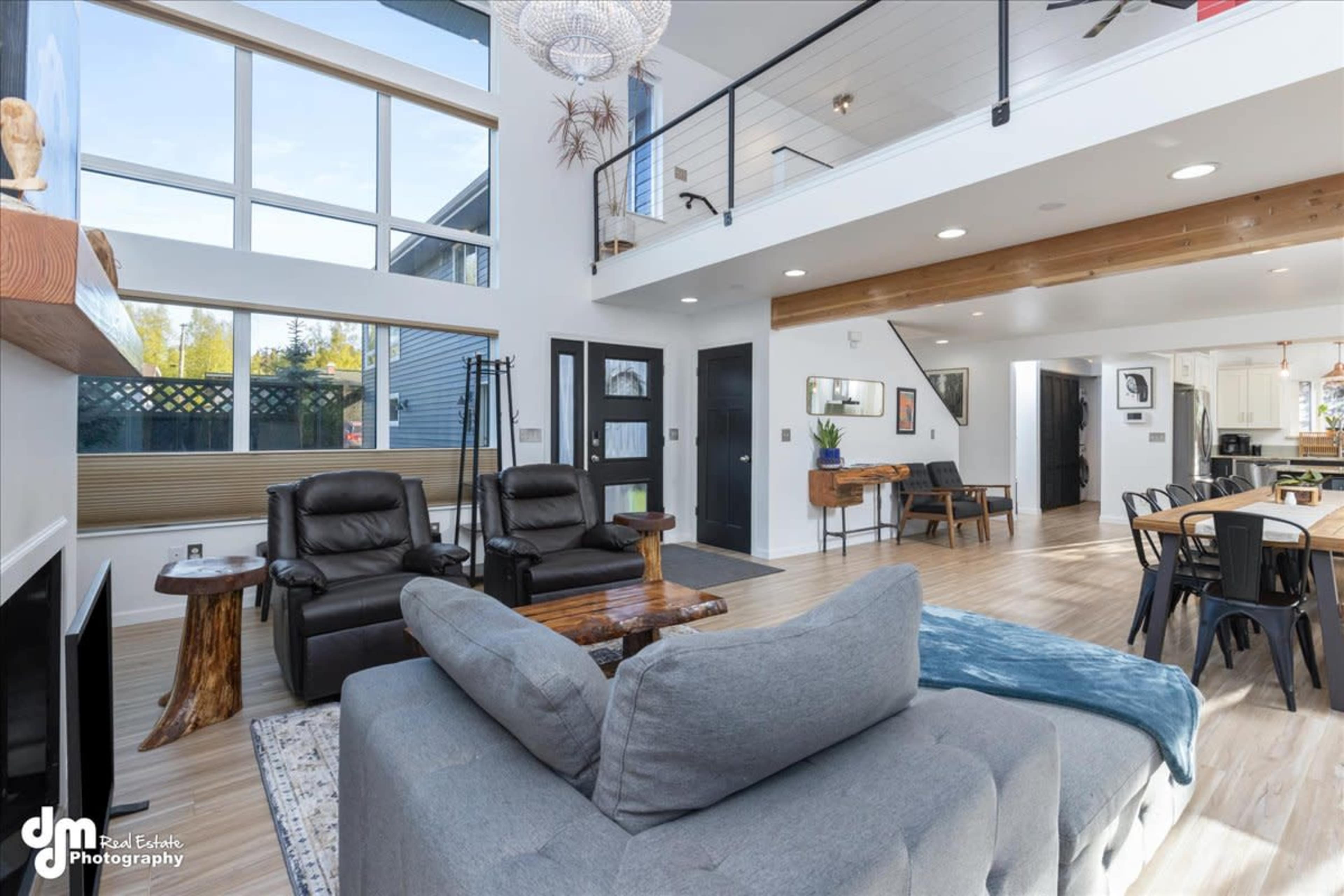 A modern, open-concept living area featuring a comfortable seating arrangement, large windows, and a dining area in a well-lit space.