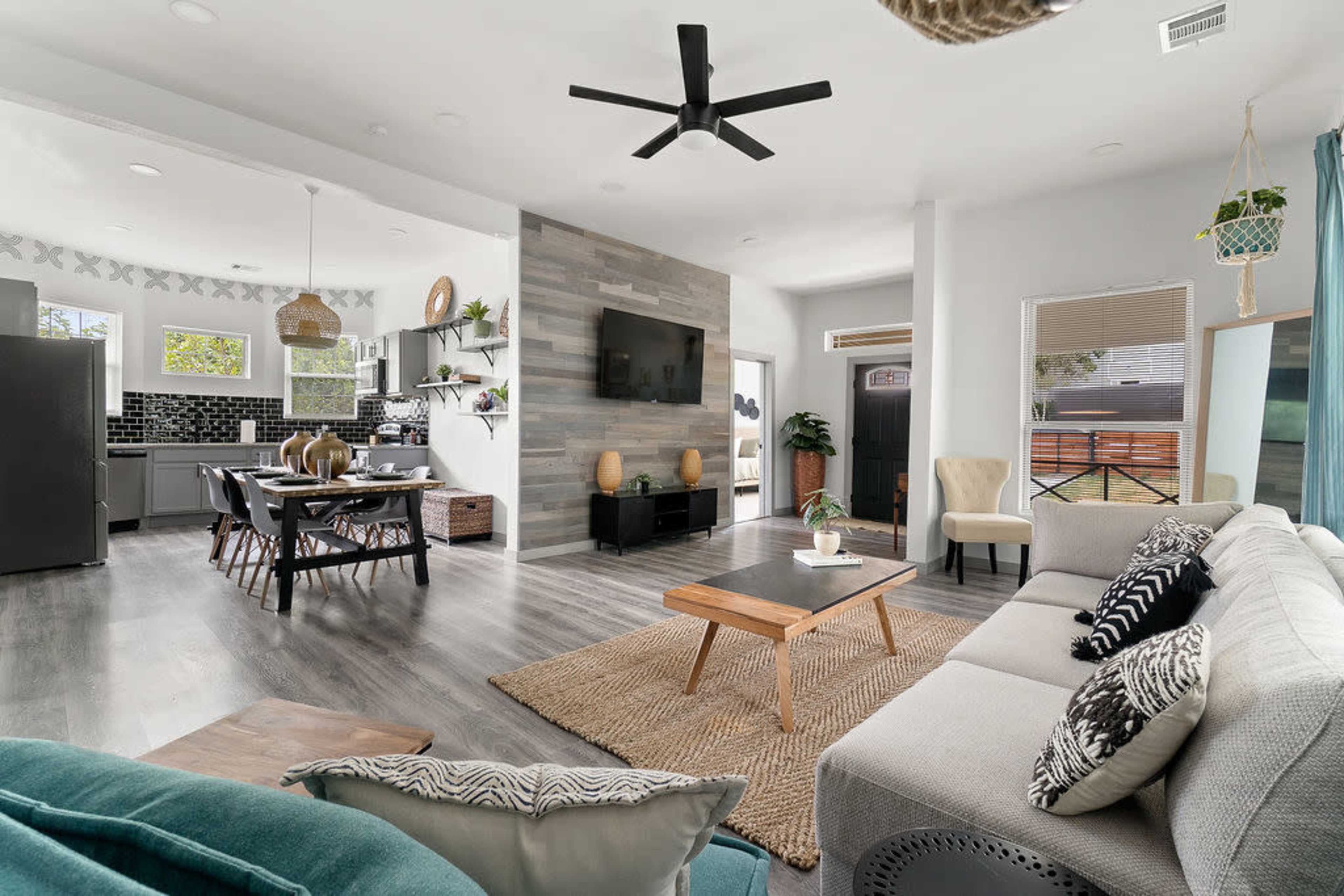 A modern, open-concept living area with a kitchen and dining space, featuring a comfortable seating arrangement, a wooden coffee table, and decorative elements.