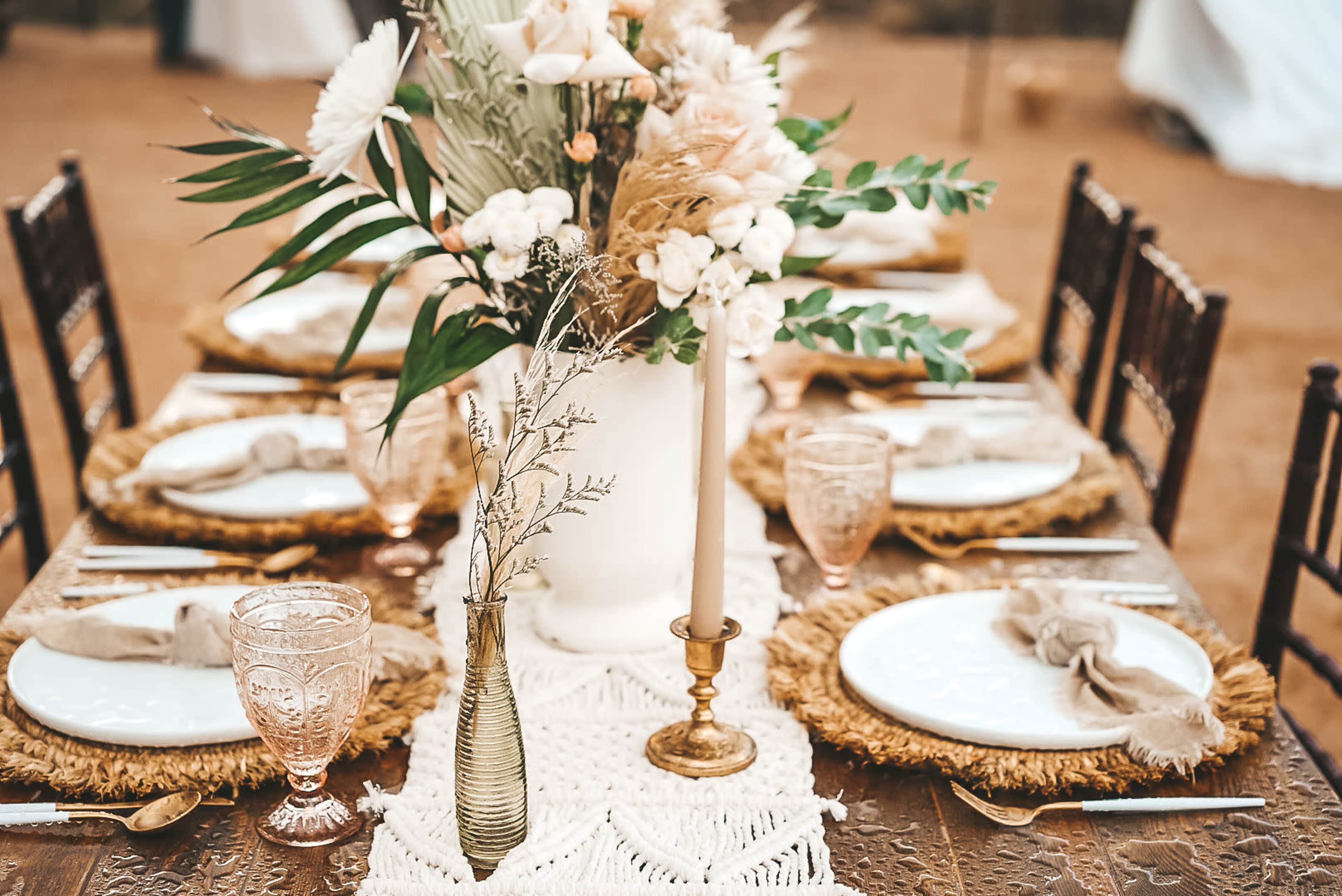 A decorated table is set with plates, glassware, and a floral centerpiece, featuring a combination of natural elements and elegant tableware.