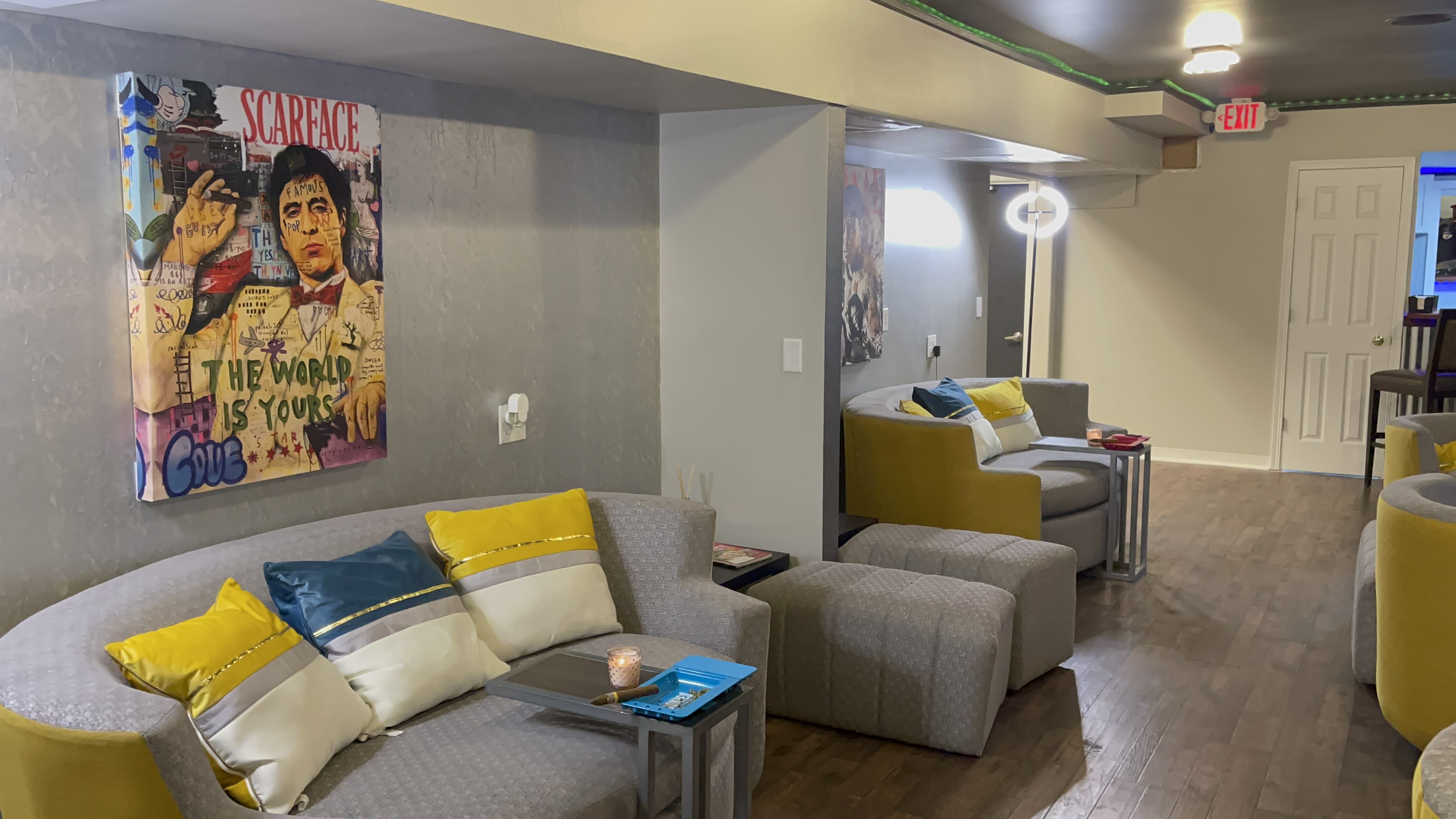 A lounge area with gray and yellow furniture, artwork on the walls, and soft lighting.