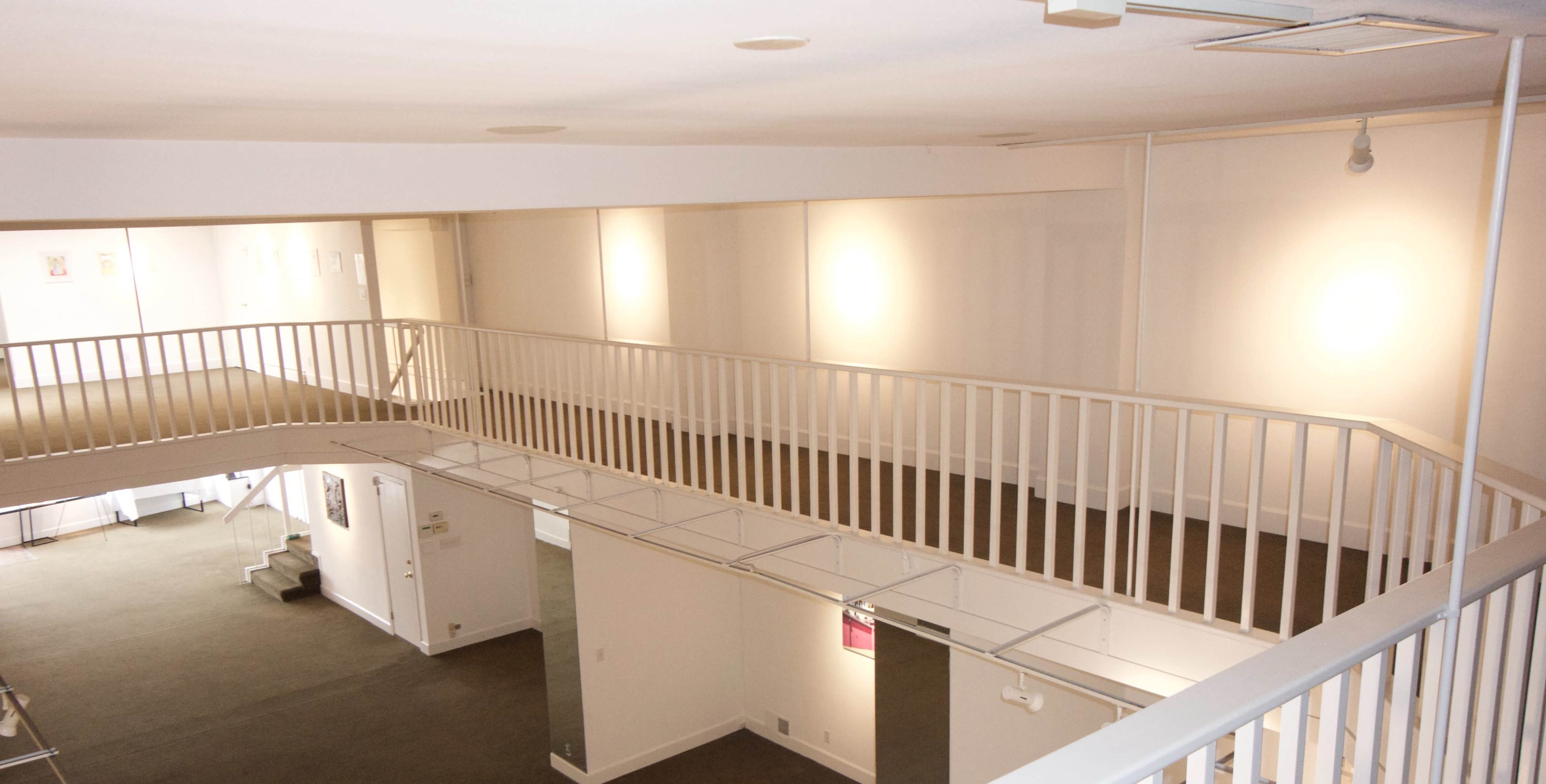 The image shows a spacious interior with a two-level design featuring a white railing overlooking a lower area.