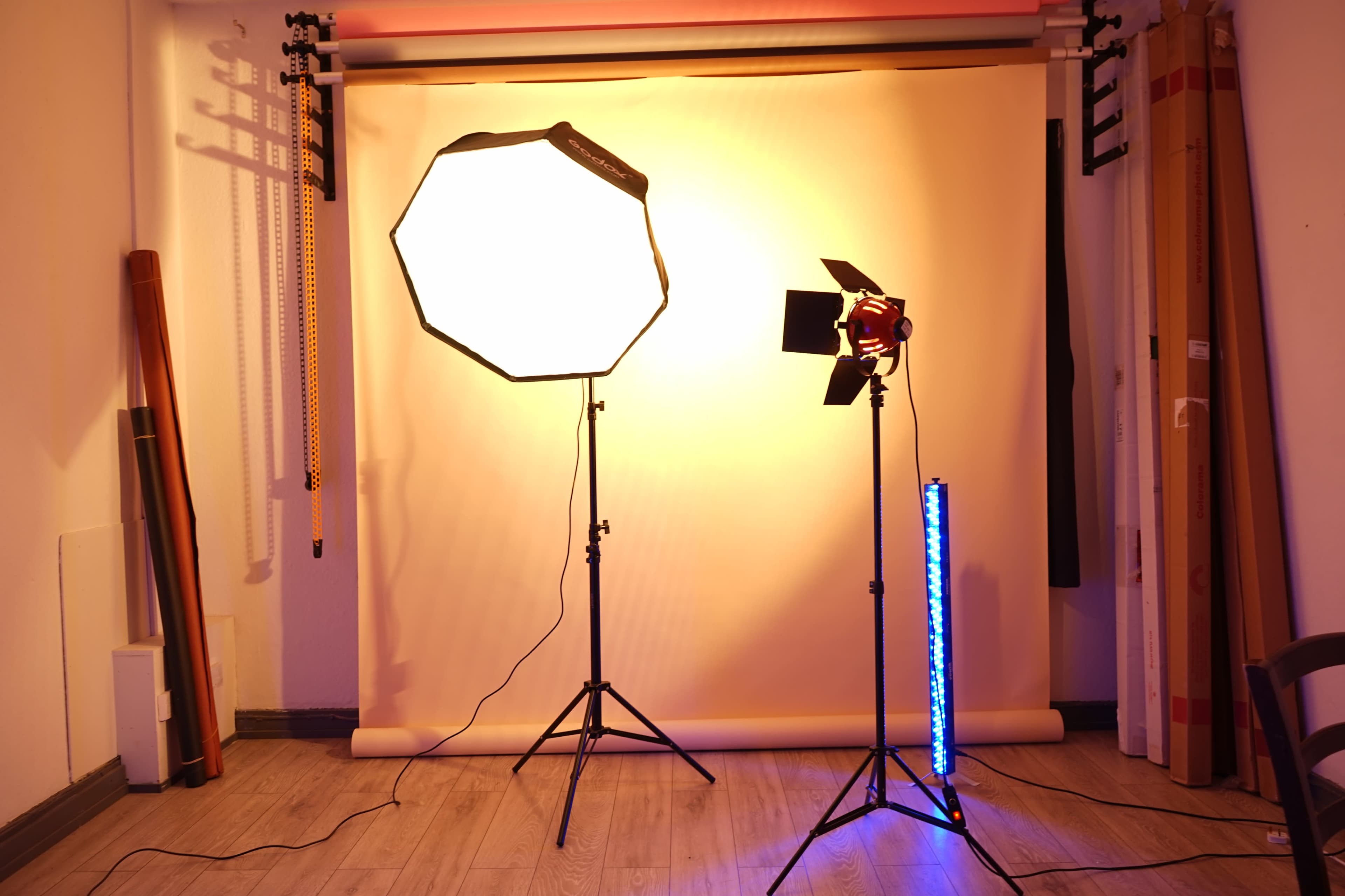 The image shows a photography studio setup with an octagonal softbox, a spotlight, and a vertical LED light against a backdrop.