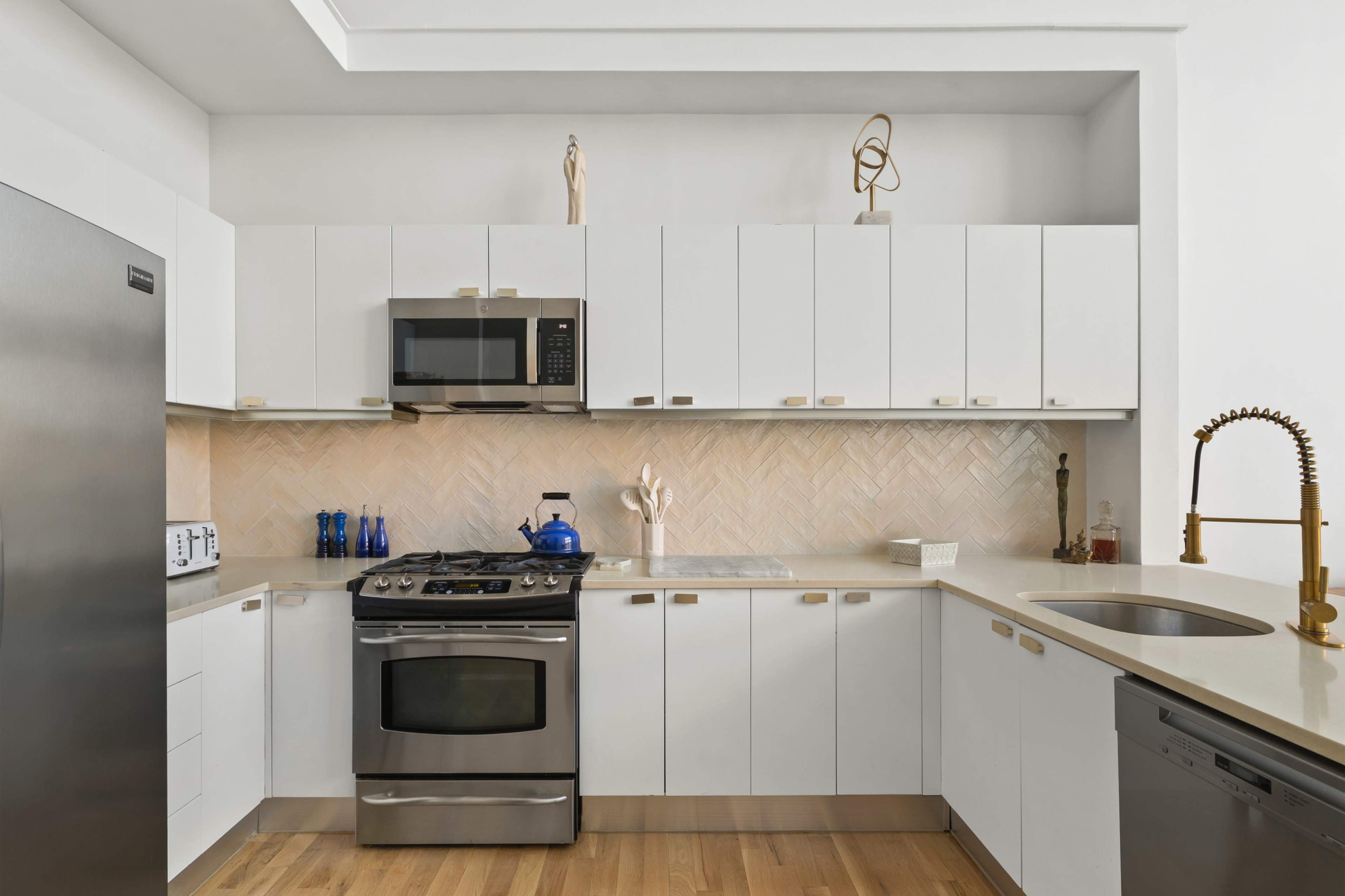 A modern kitchen features white cabinetry, stainless steel appliances, a herringbone backsplash, and light wood flooring.