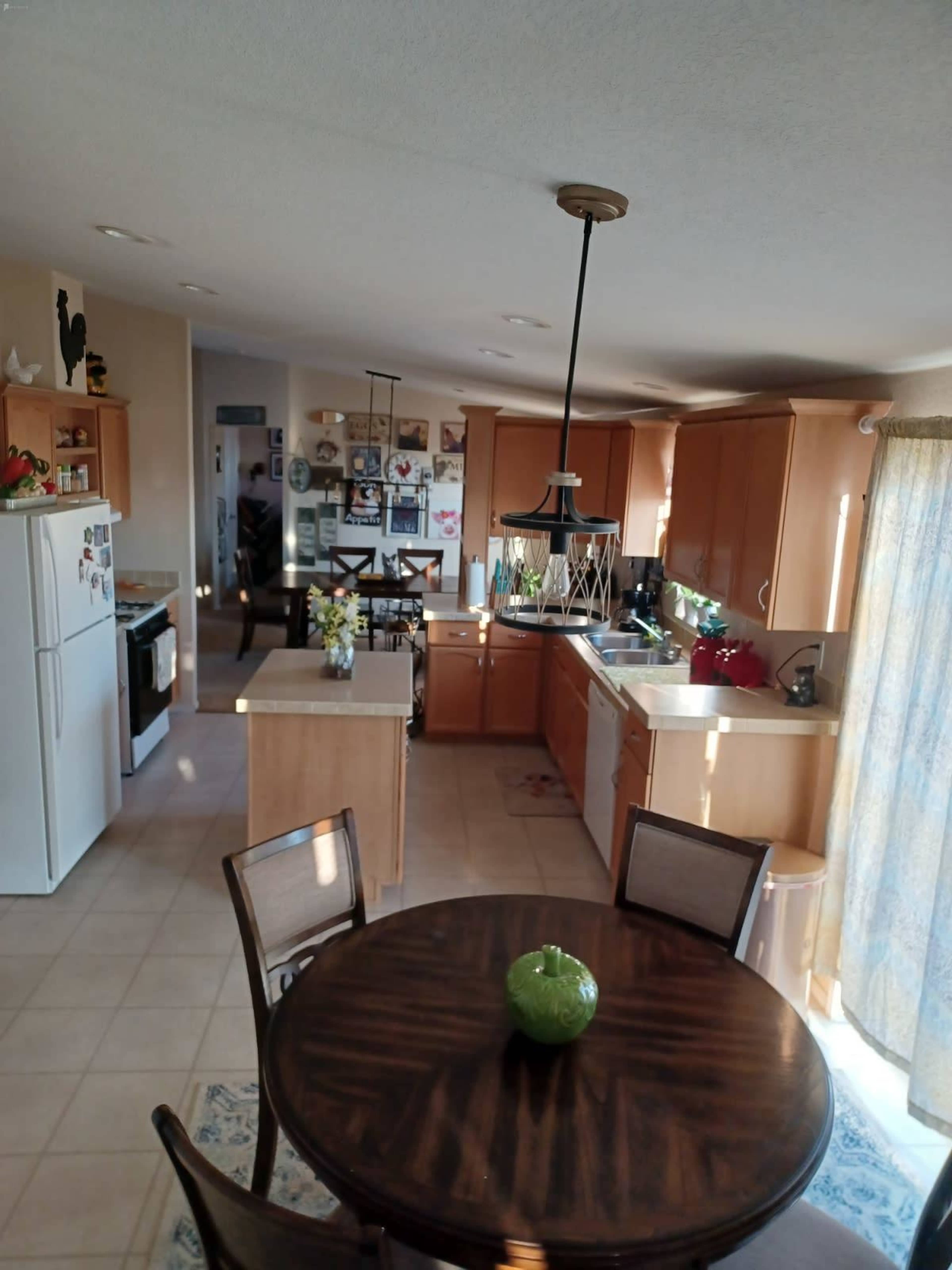 A modern kitchen with wooden cabinets, a round dining table, and a combination of appliances, all set in a well-lit space.
