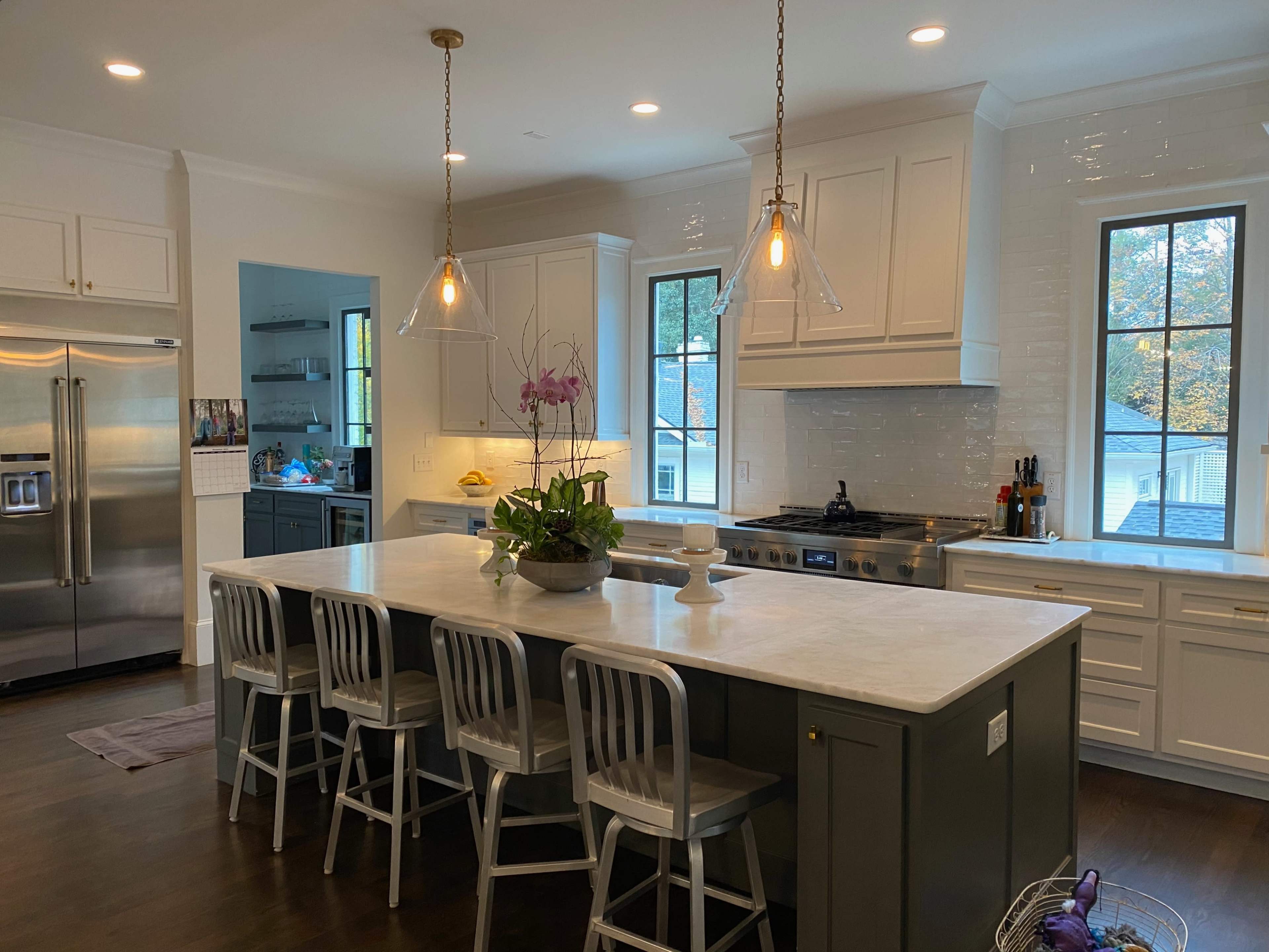 A modern kitchen features a large island with seating, stainless steel appliances, and pendant lighting.