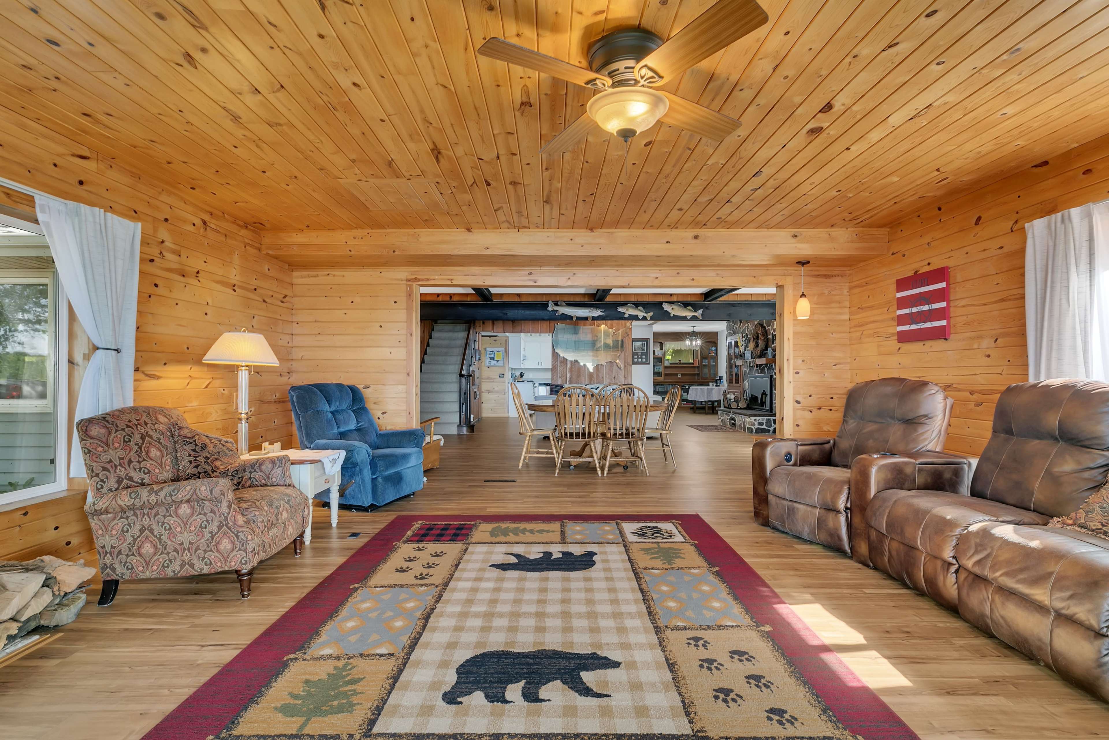 The image shows a cozy wooden living space featuring a patterned area rug with bear designs, comfortable seating, and a ceiling fan.