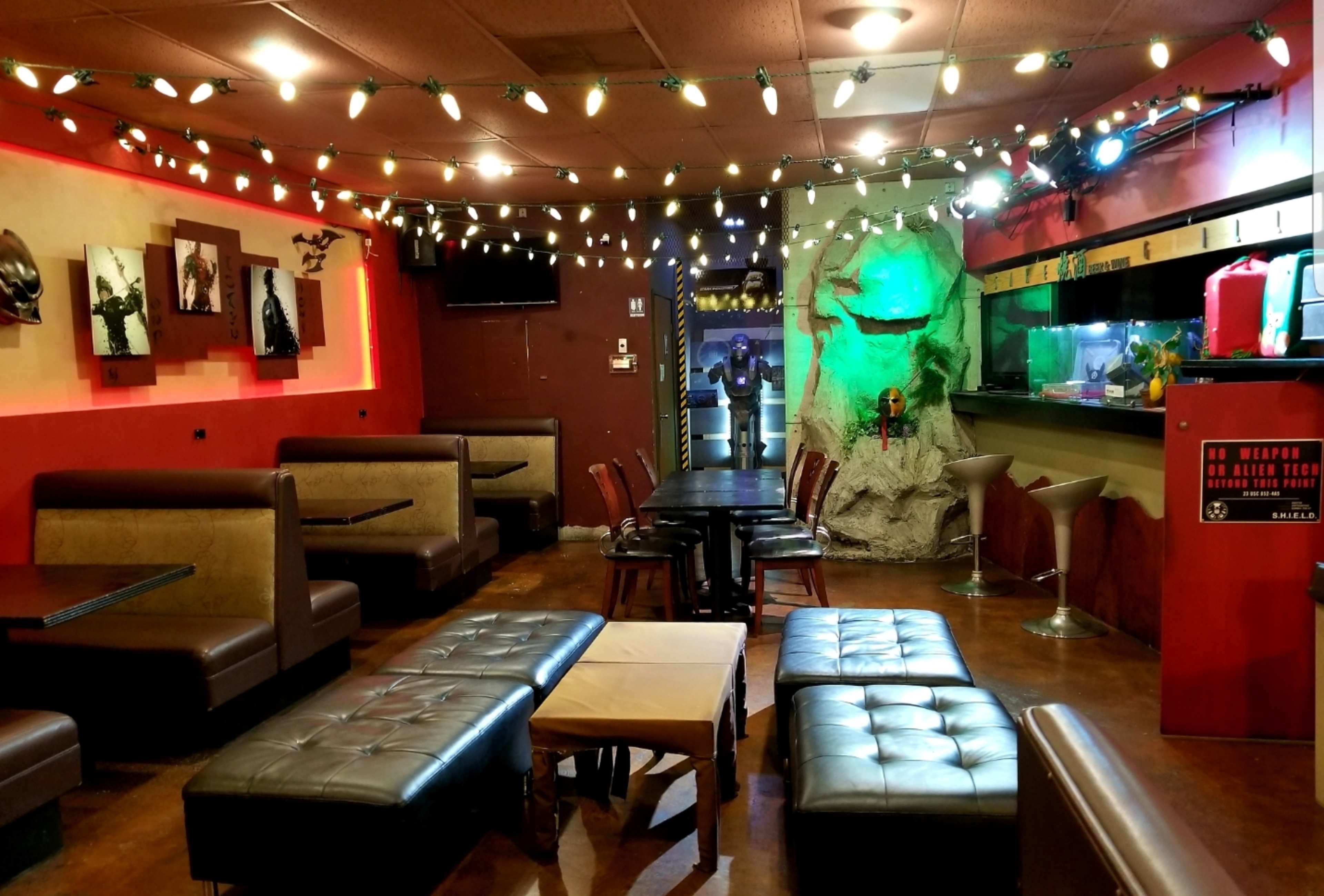 The interior of a dimly lit lounge features comfortable seating, decorative lighting, and a bar area with a unique rock formation backdrop.