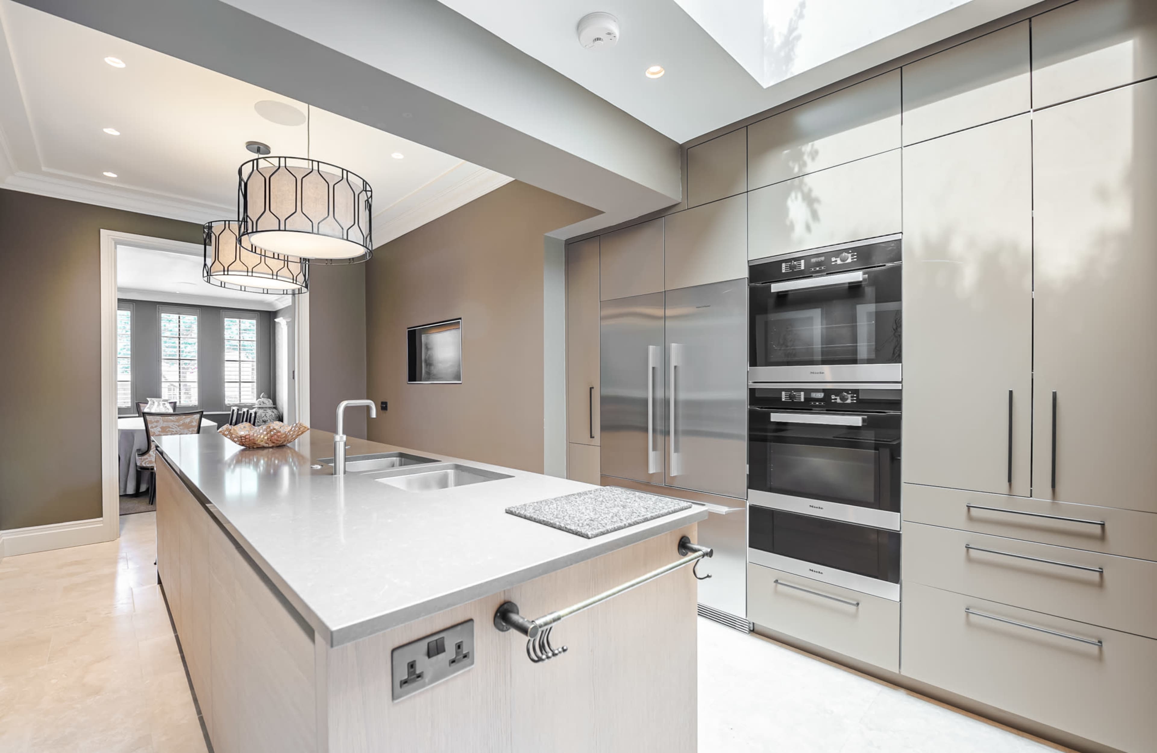 A modern kitchen featuring a central island with a sink, sleek cabinetry, and built-in stainless steel appliances.