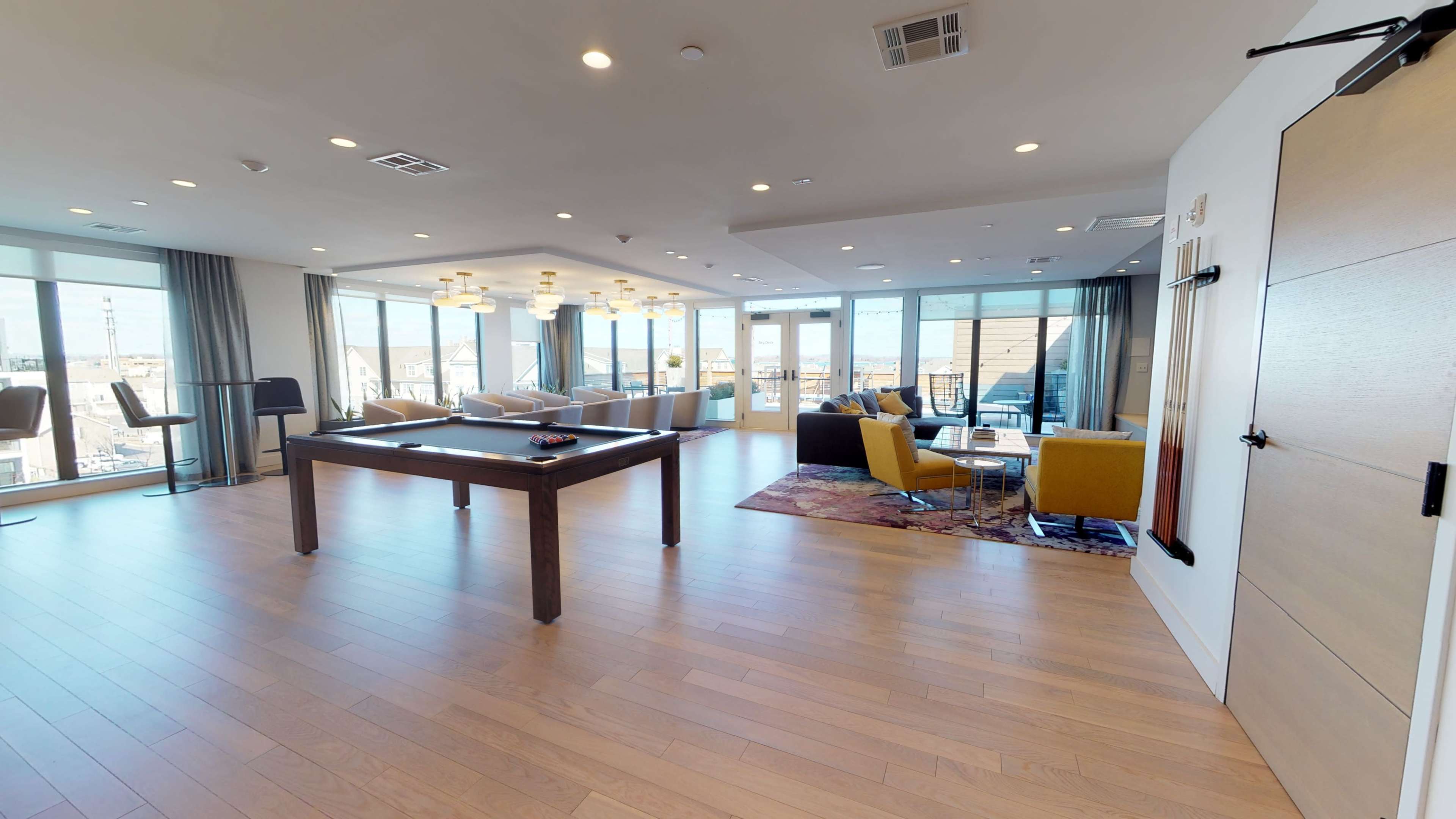 A spacious indoor lounge area with large windows, a pool table, and various seating arrangements.