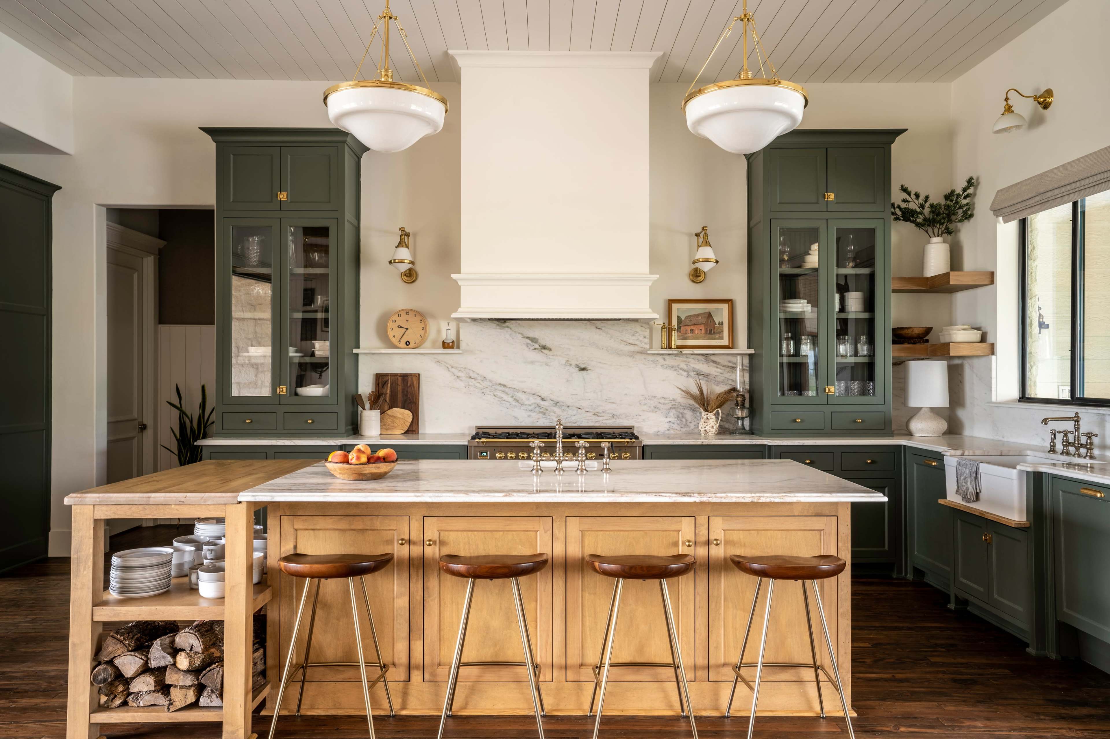 The kitchen features green cabinetry, a large central island with a marble countertop, and wooden bar stools.