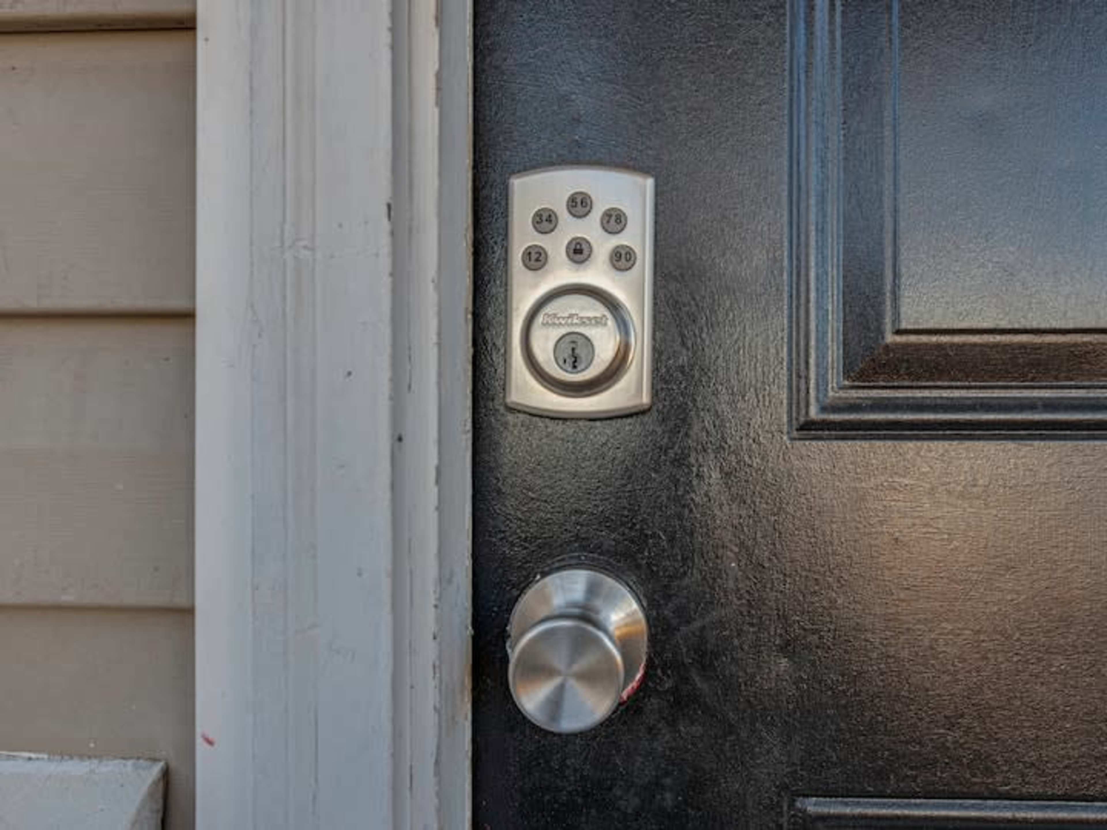 A close-up of a black door featuring a keypad lock and a round door knob.