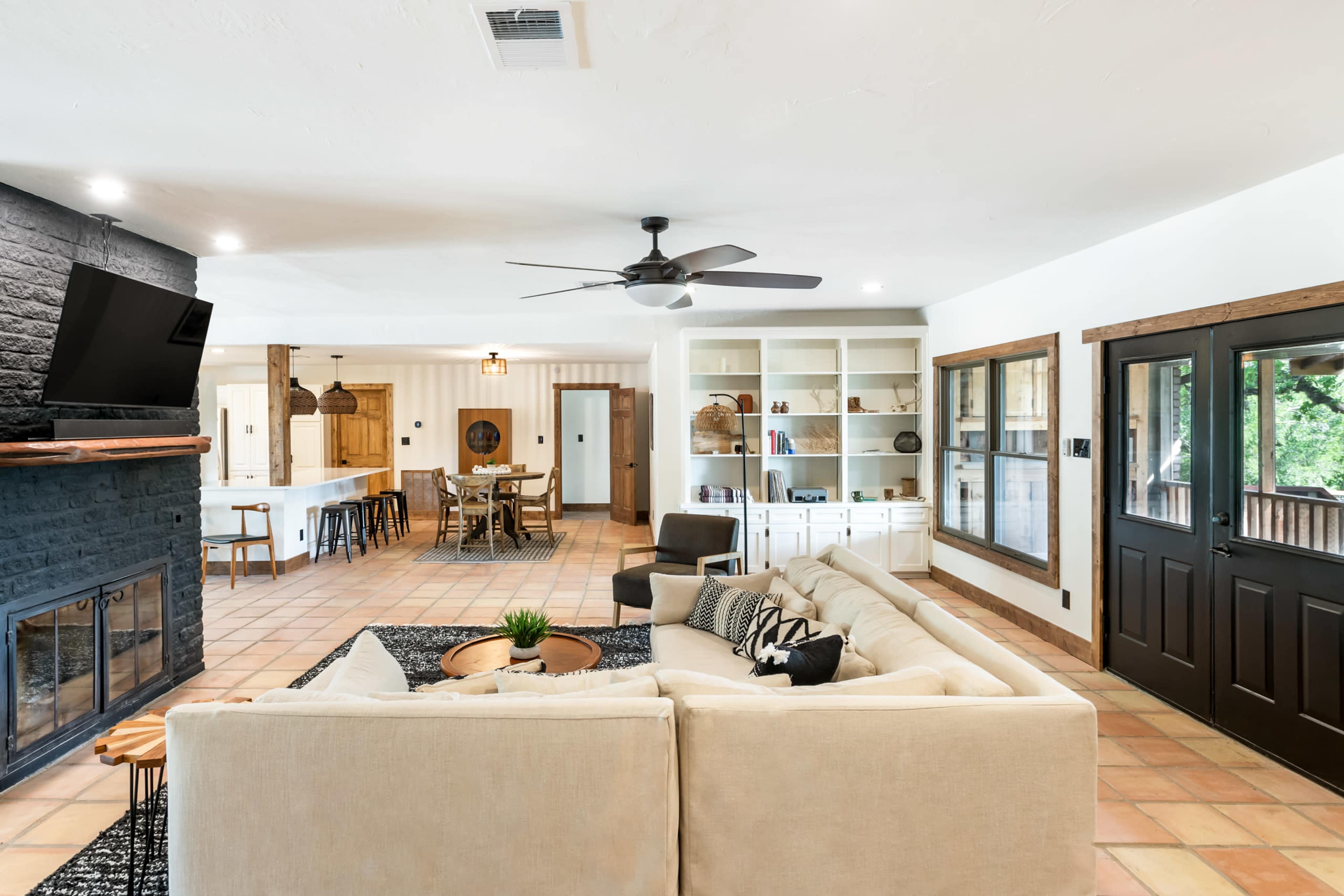 A spacious living room featuring a large sectional sofa, a fireplace, and an open layout leading to a dining area and kitchen.